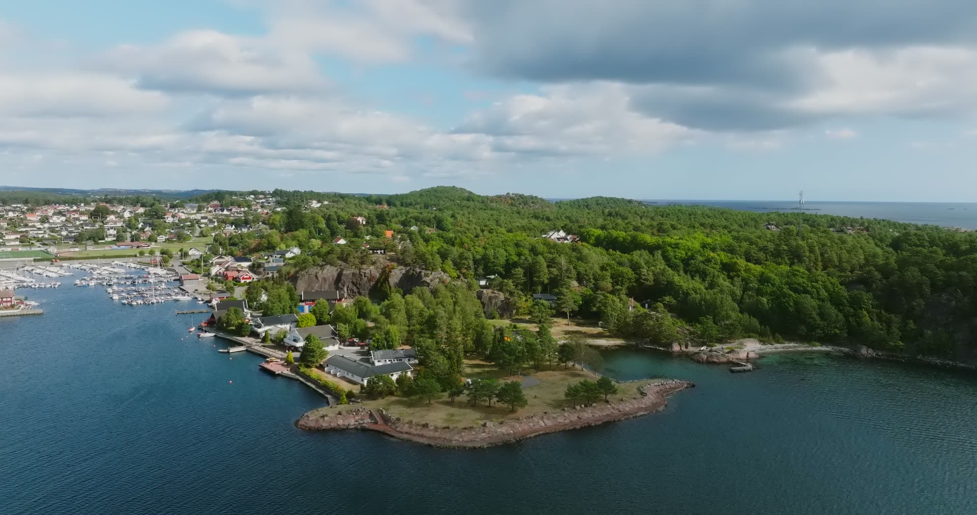 Wooded headland beside marina and docks, Fevik, Norway