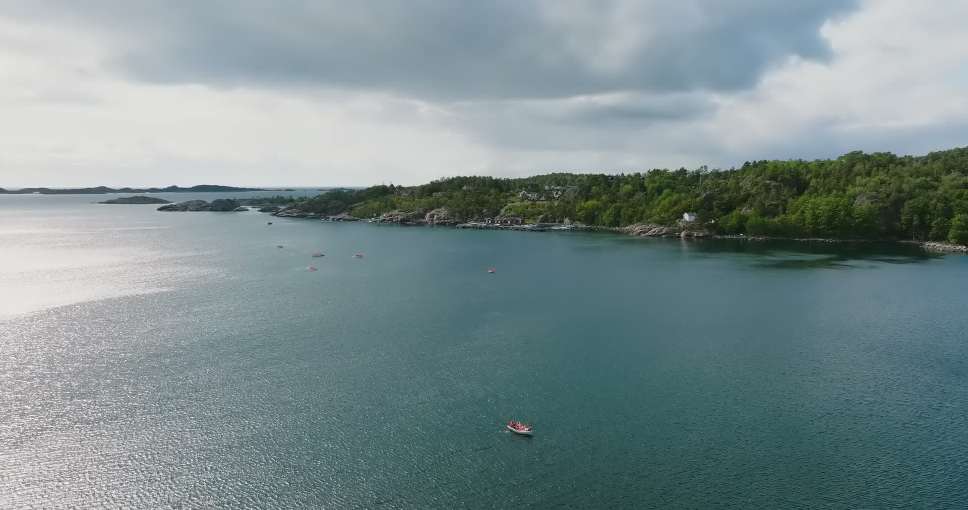 Red boat crossing bay off wooded shore, Fevik, Norway