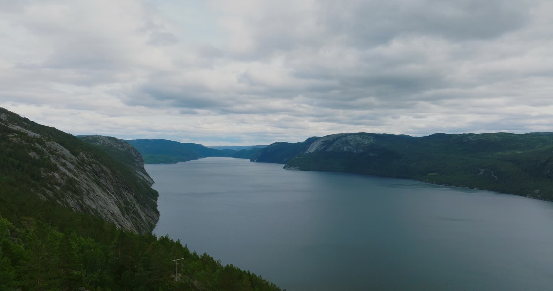 Roadside pines above long cliff-lined lake, Fyresdal, Norway