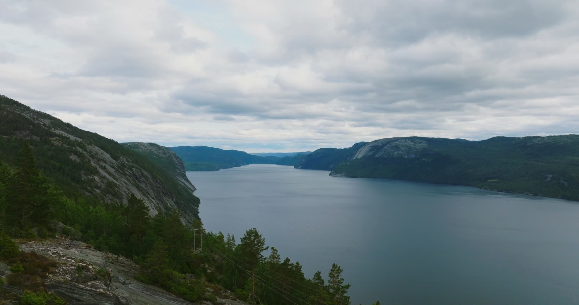 Power line over pines above lake cliffs, Fyresdal, Norway