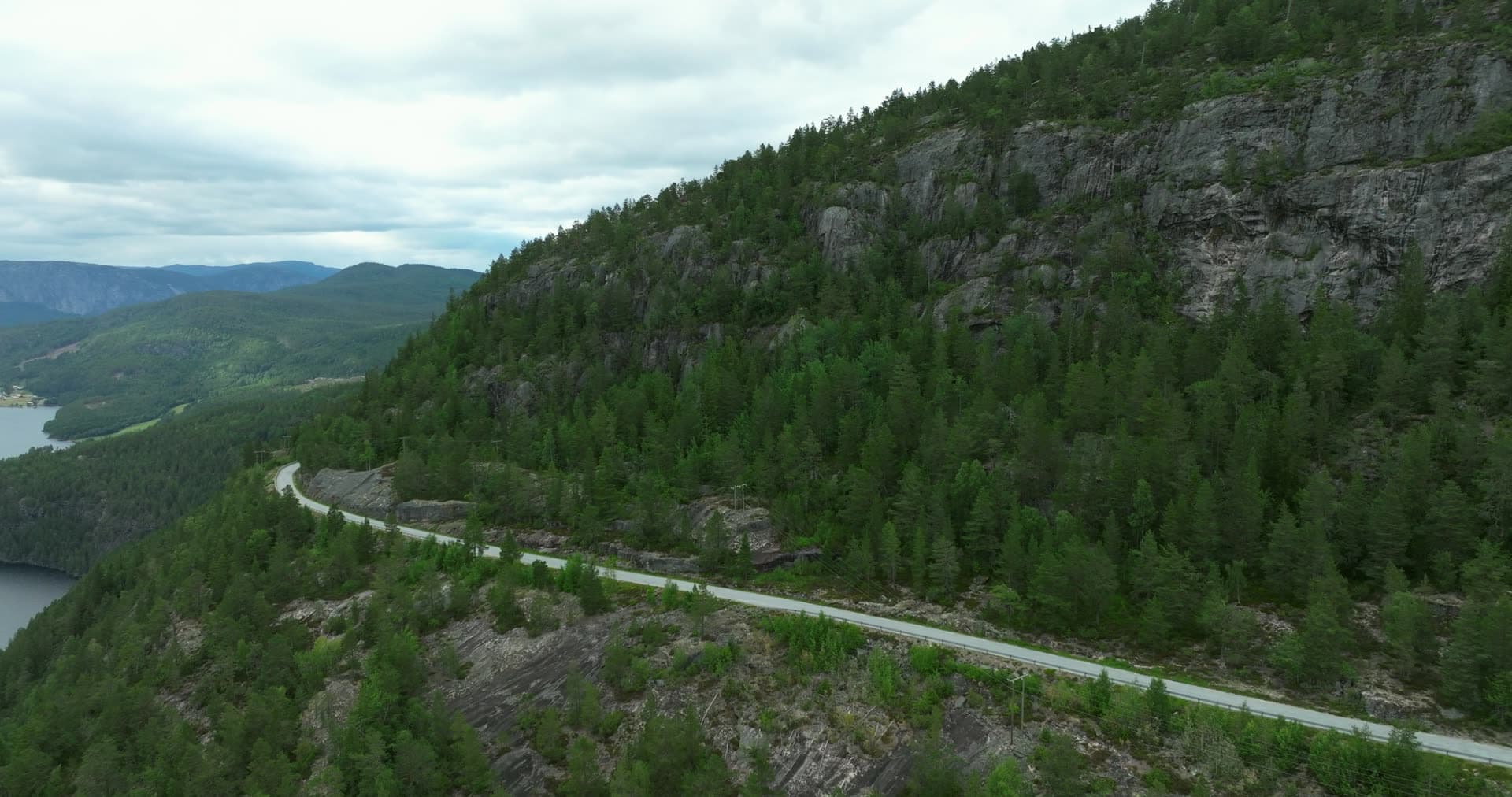 Road cut into cliffside above lake, Fyresdal, Norway