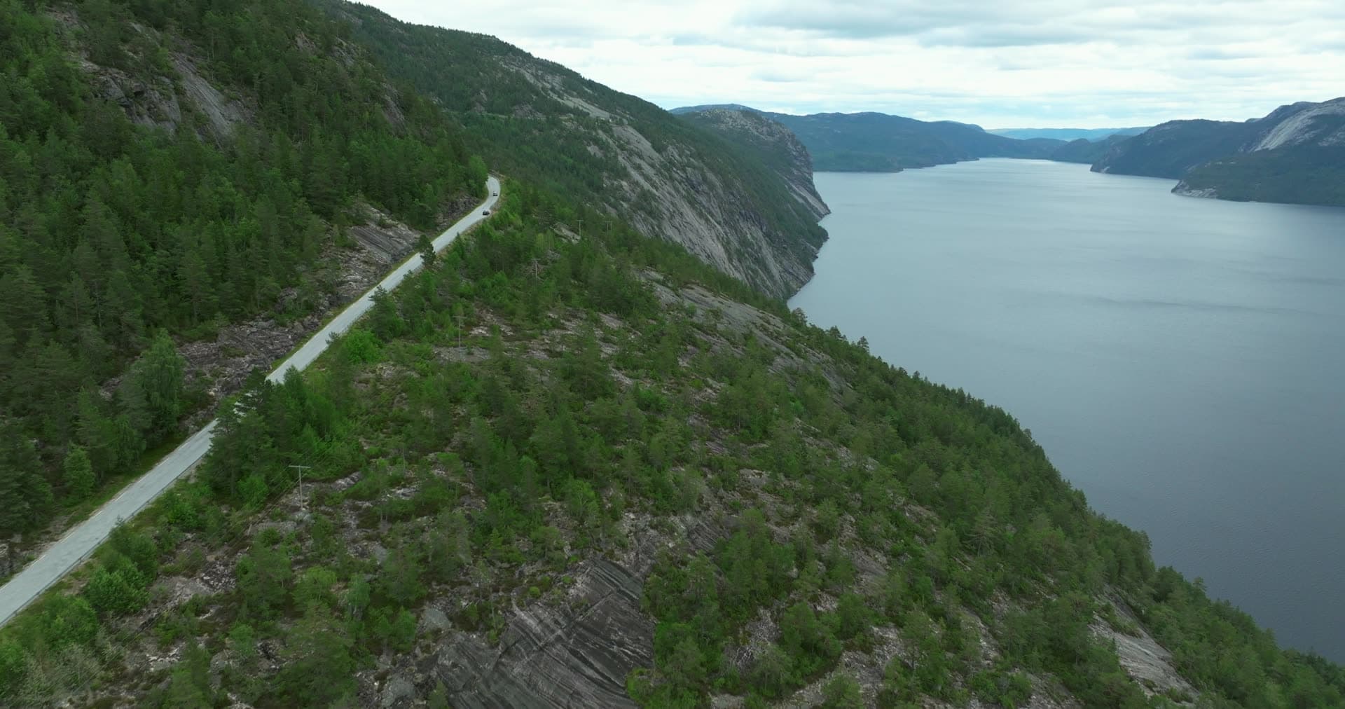 Car on hillside road above lake, Fyresdal, Norway