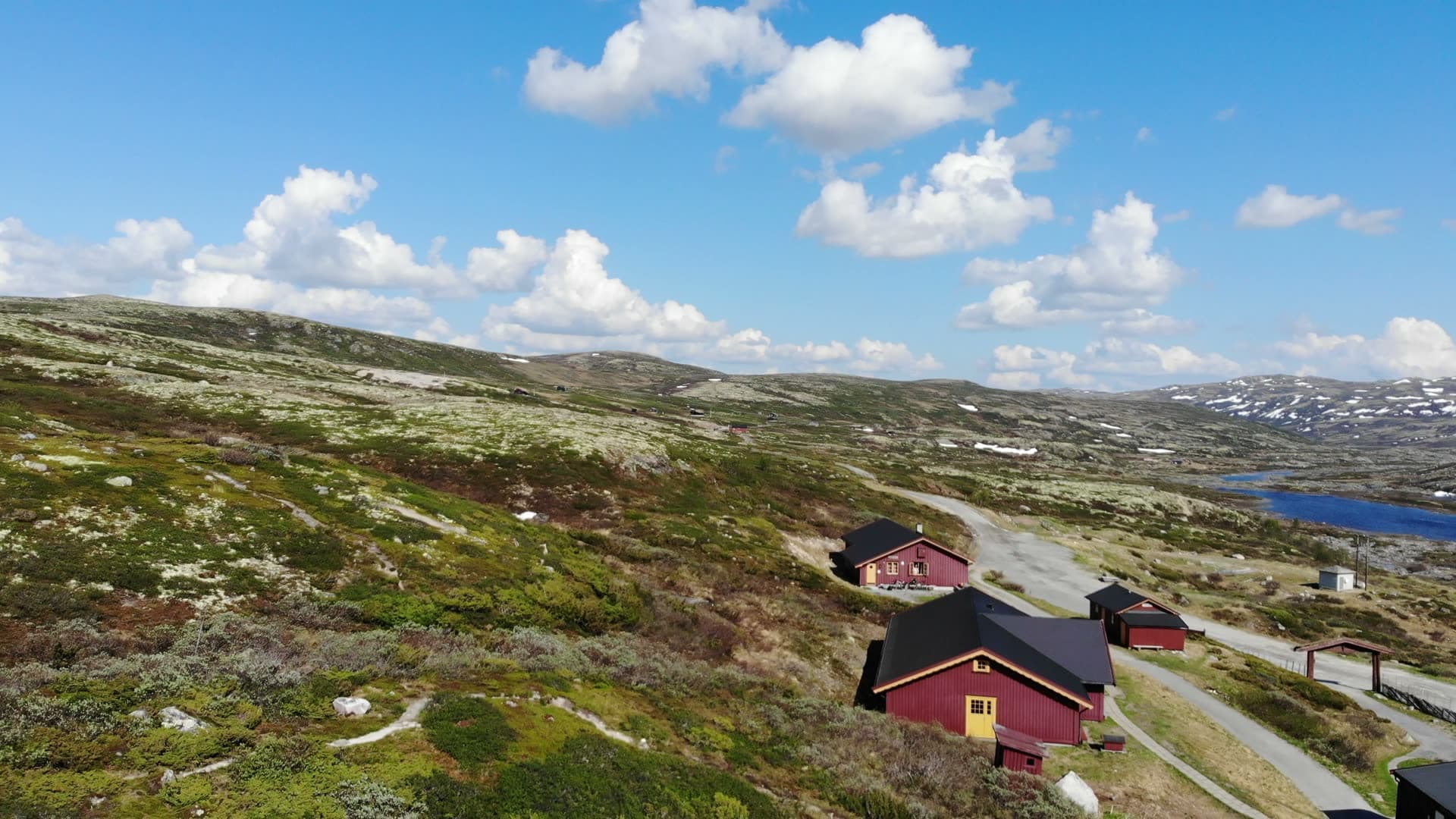 Red cabins on mossy plateau by a lake, Gaustatoppen, Norway