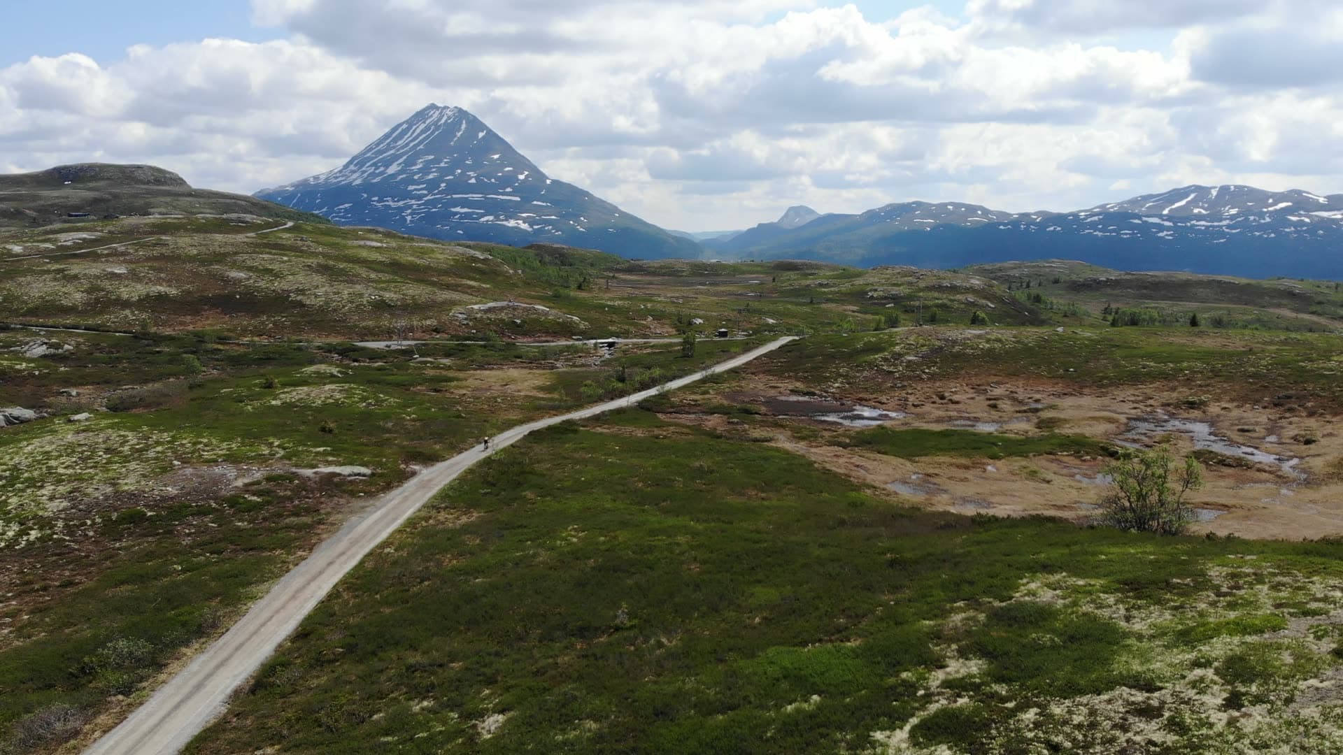Gravel road across moorland to peaked mountain, Gaustatoppen, Norway