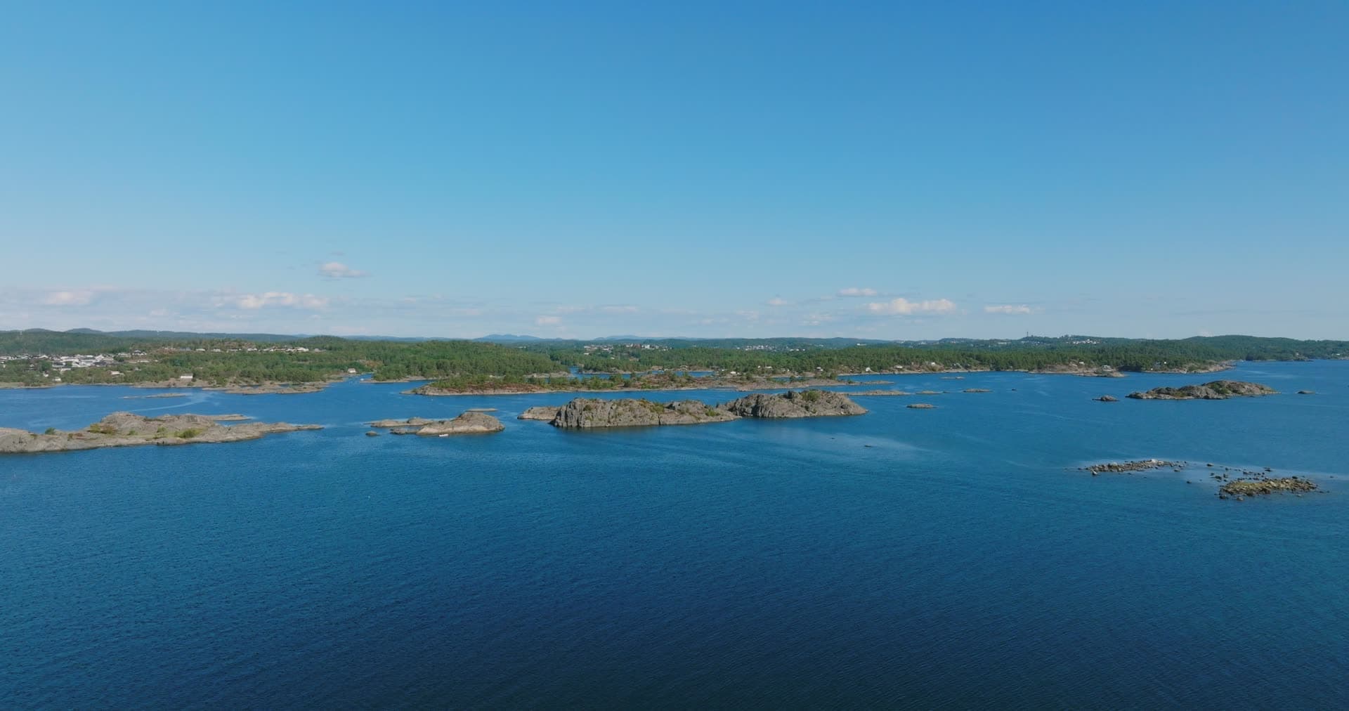 Bare rock skerries off wooded shoreline, Hasseltangen, Norway
