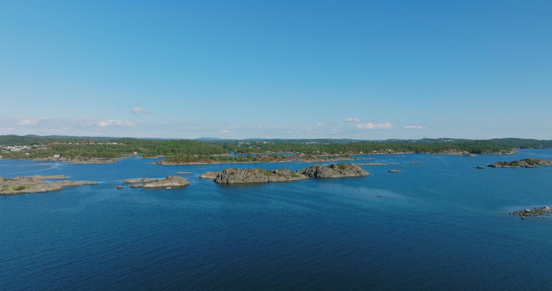 Bare rocky skerries off wooded shoreline, Hasseltangen, Norway