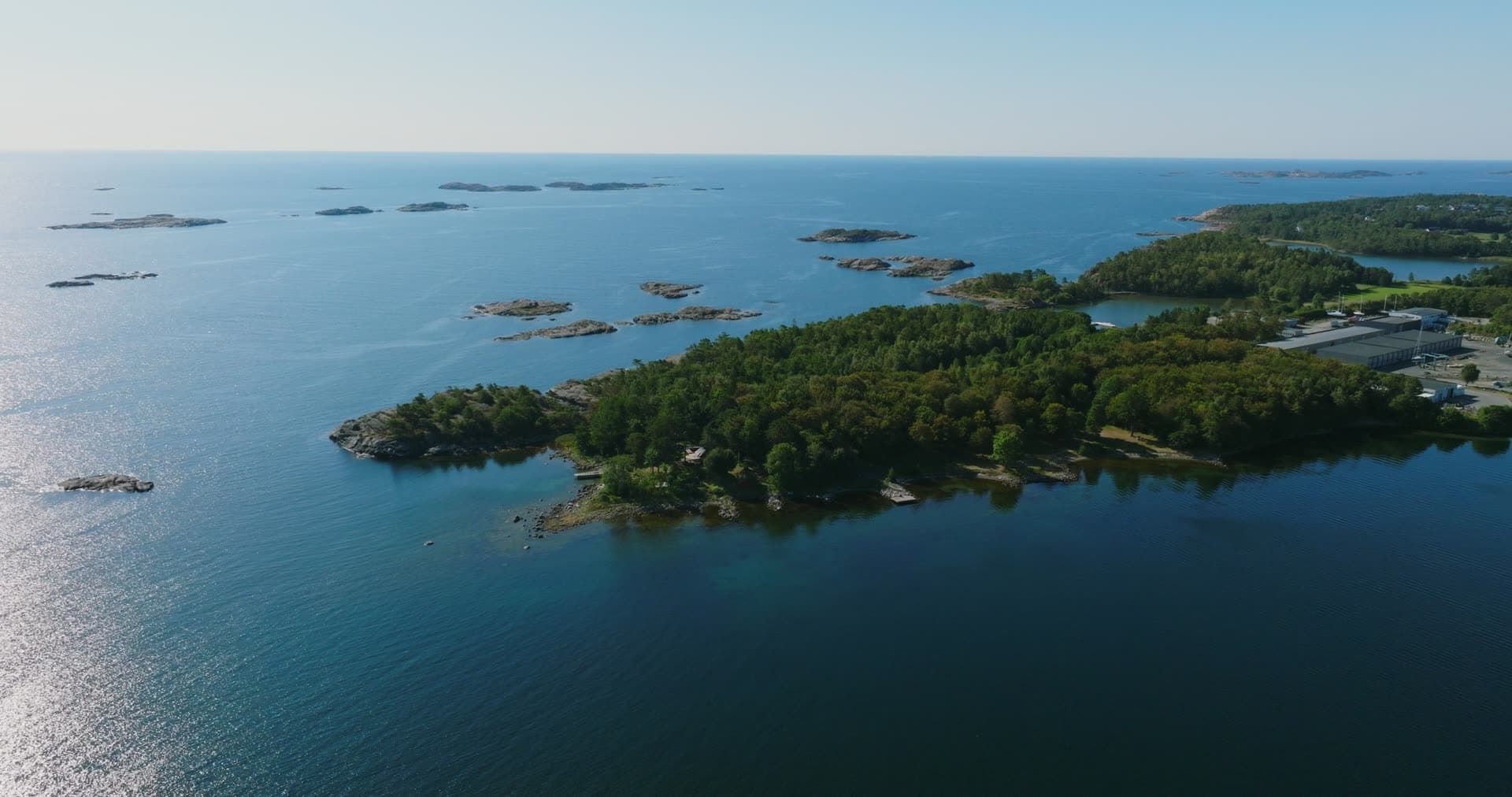 Wooded headland, skerries and industrial sheds, Hasseltangen, Norway