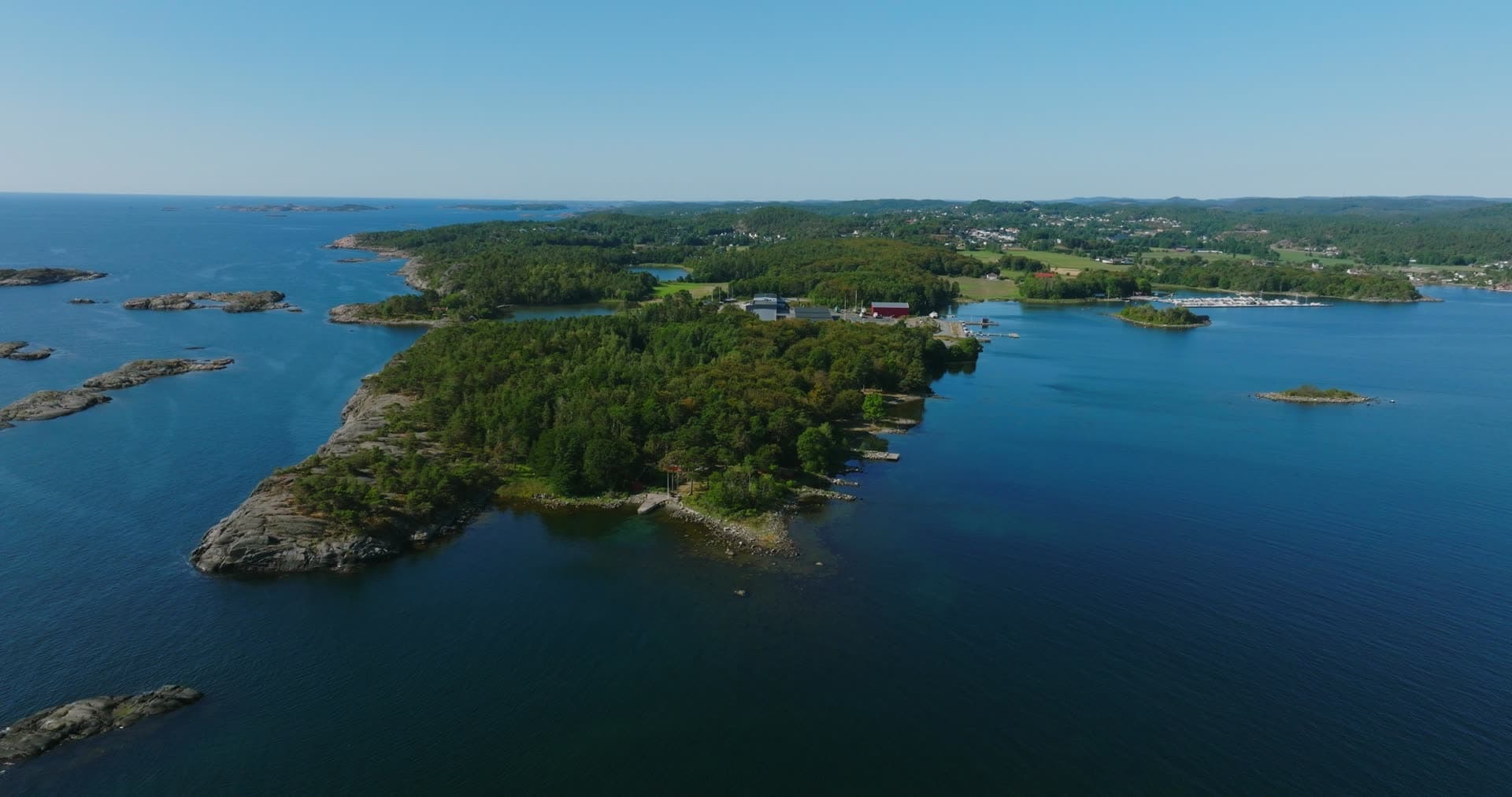 Wooded headland with red barn and marina, Hasseltangen, Norway