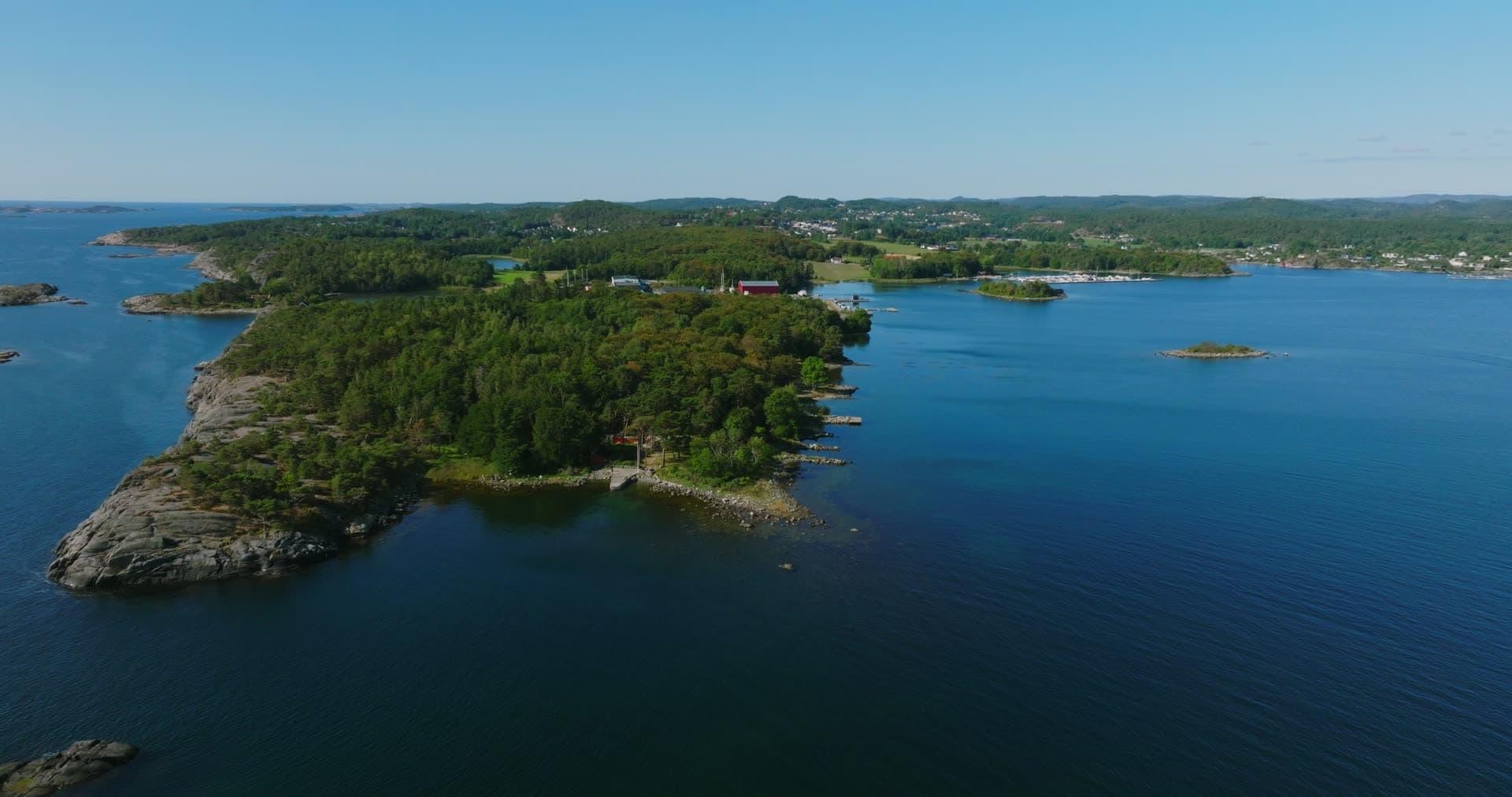 Wooded headland with small jetties and rocky shore, Hasseltangen, Norway