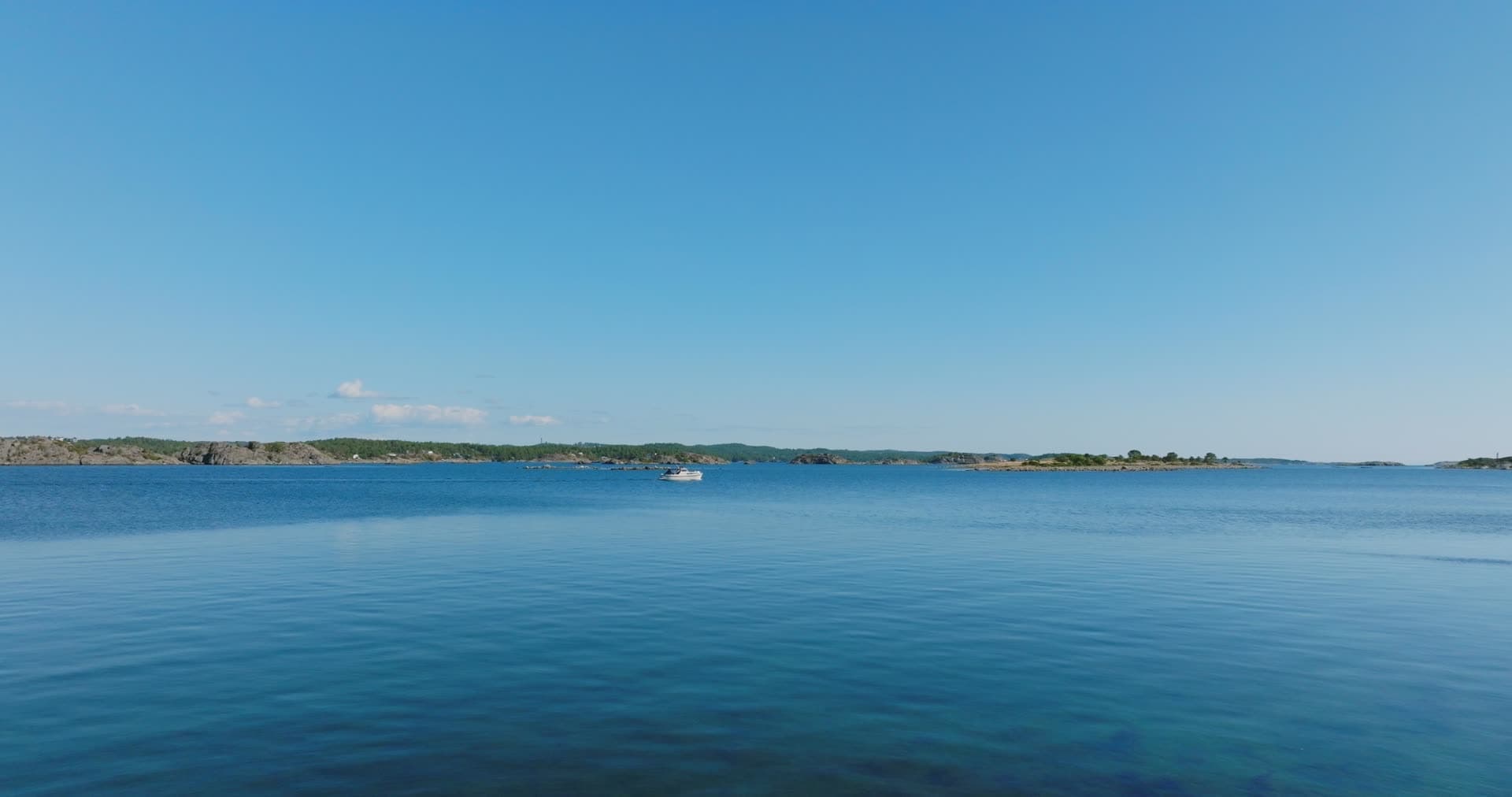 Lone white boat on calm water off islets, Hasseltangen, Norway