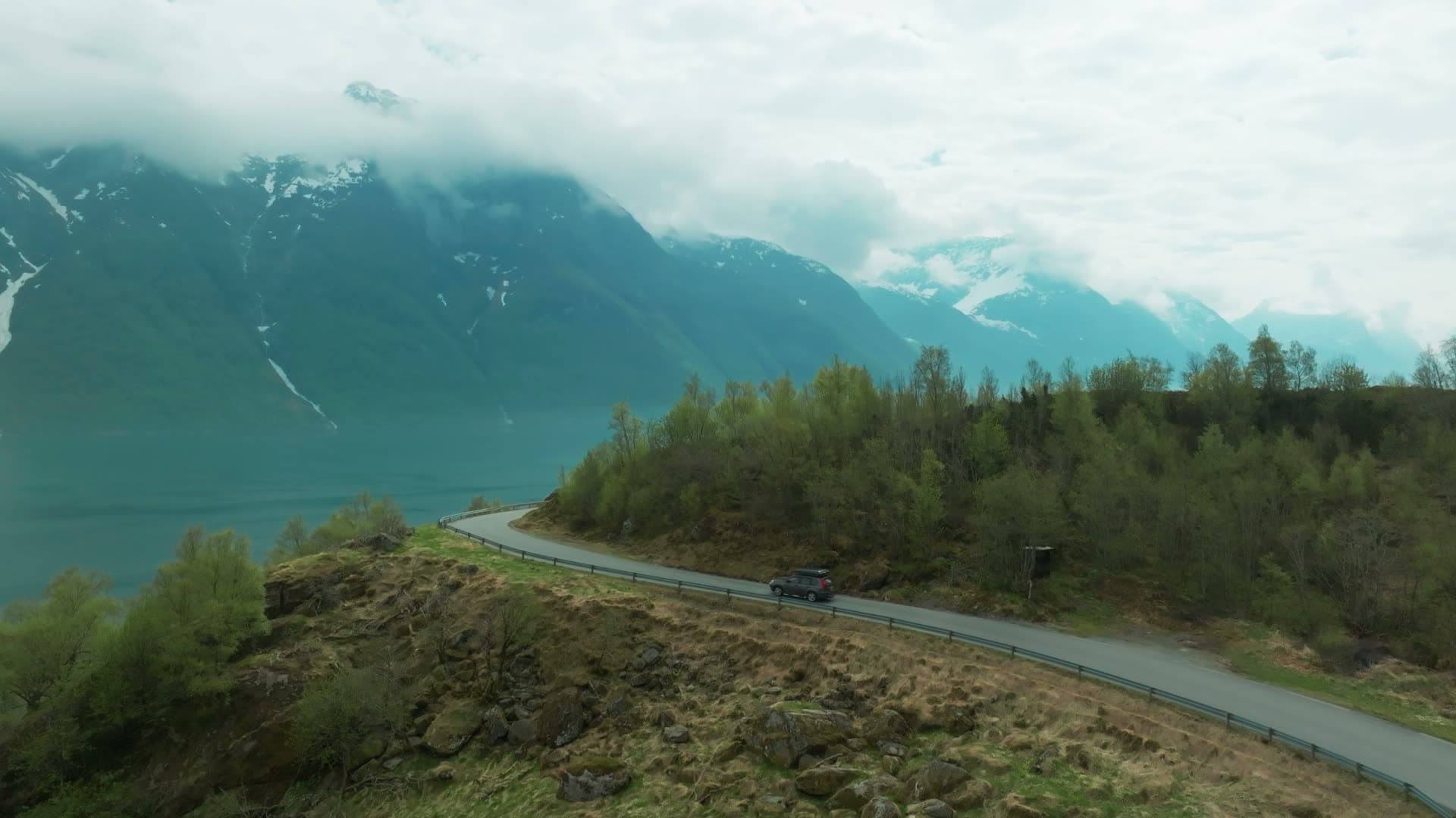 Car on clifftop road above misty fjord, Hjørundfjorden, Norway
