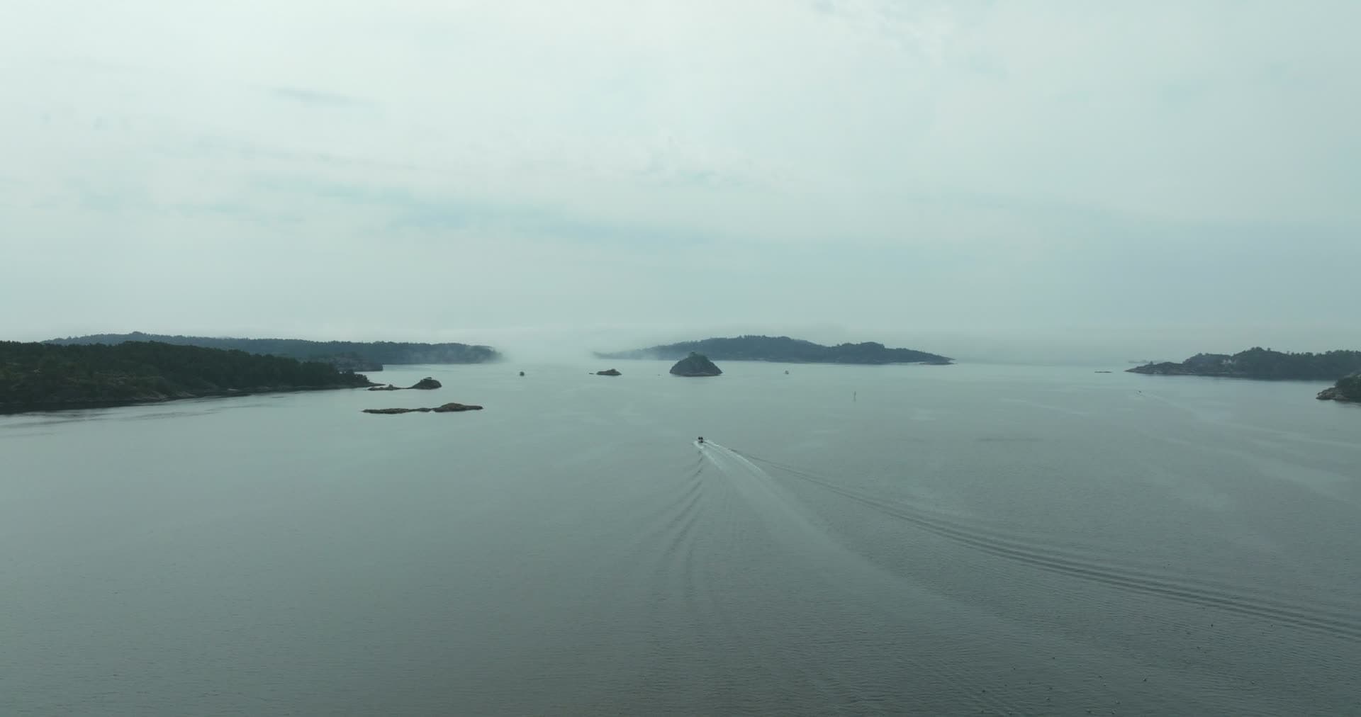 Speedboat wake between skerries in haze, Høllen, Norway
