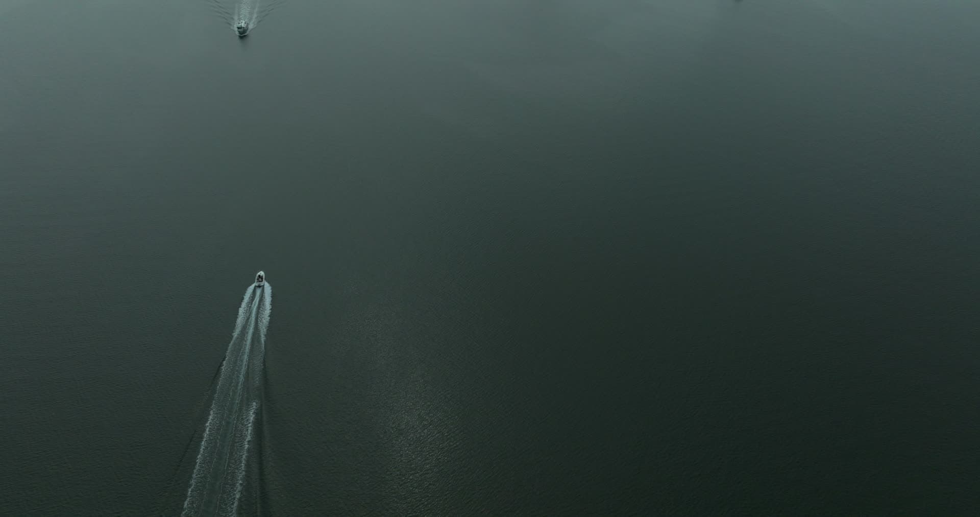 Speedboats leaving wakes on dark open water, Høllen, Norway