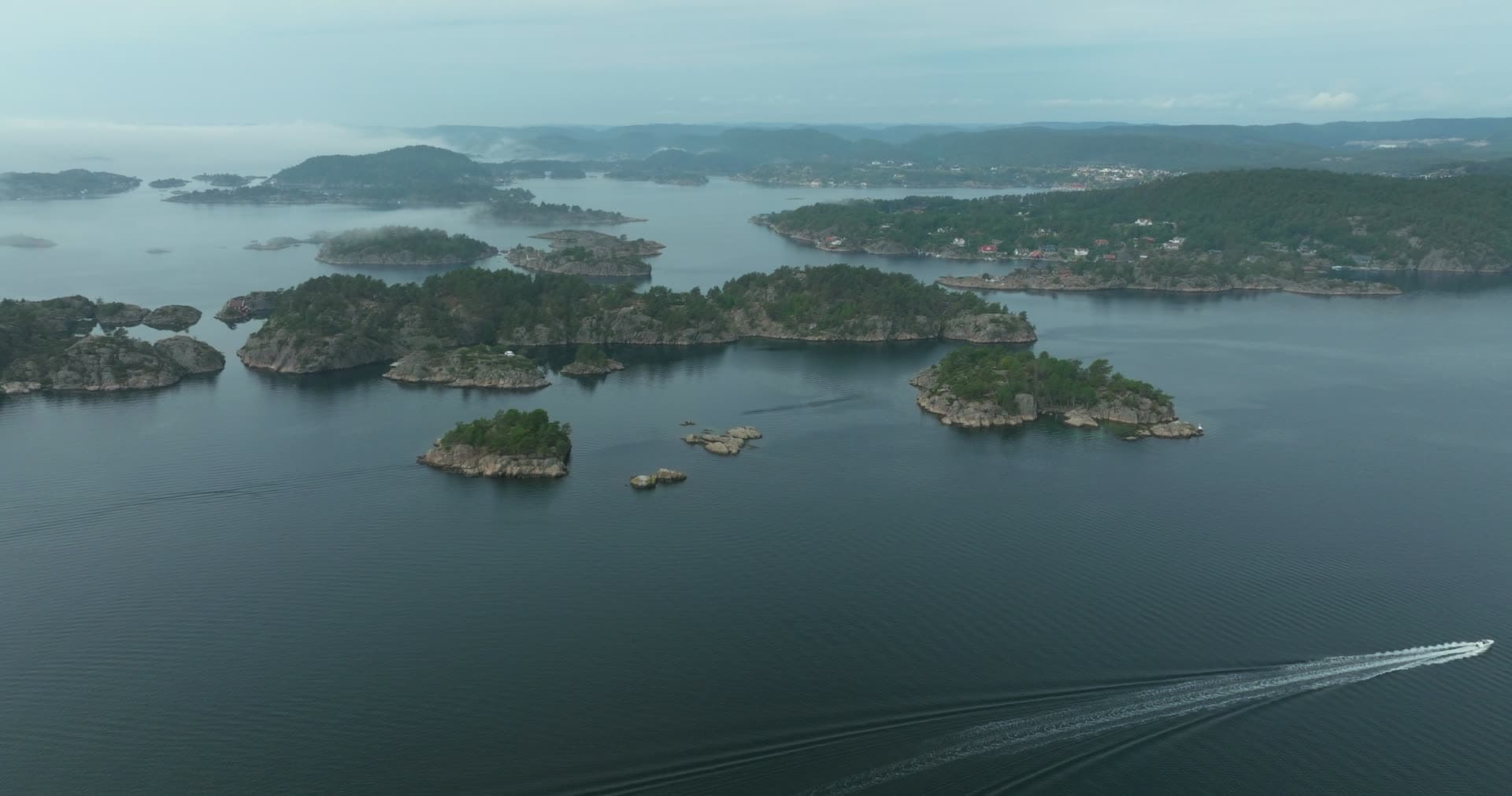 Speedboat wake between wooded islets, Høllen, Norway