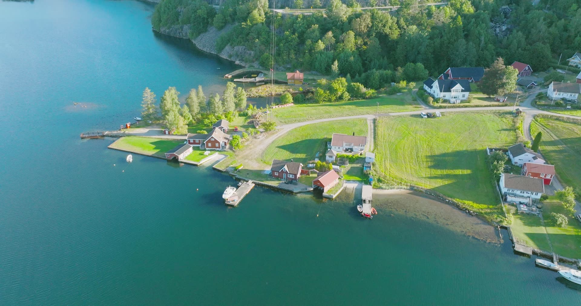 Mown green field sloping to boat jetties, Holmen, Norway