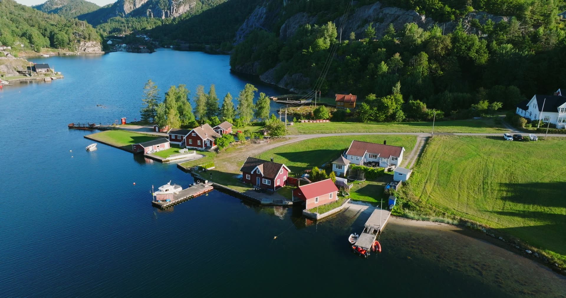 Red boathouses and jetties on grassy point, Holmen, Norway