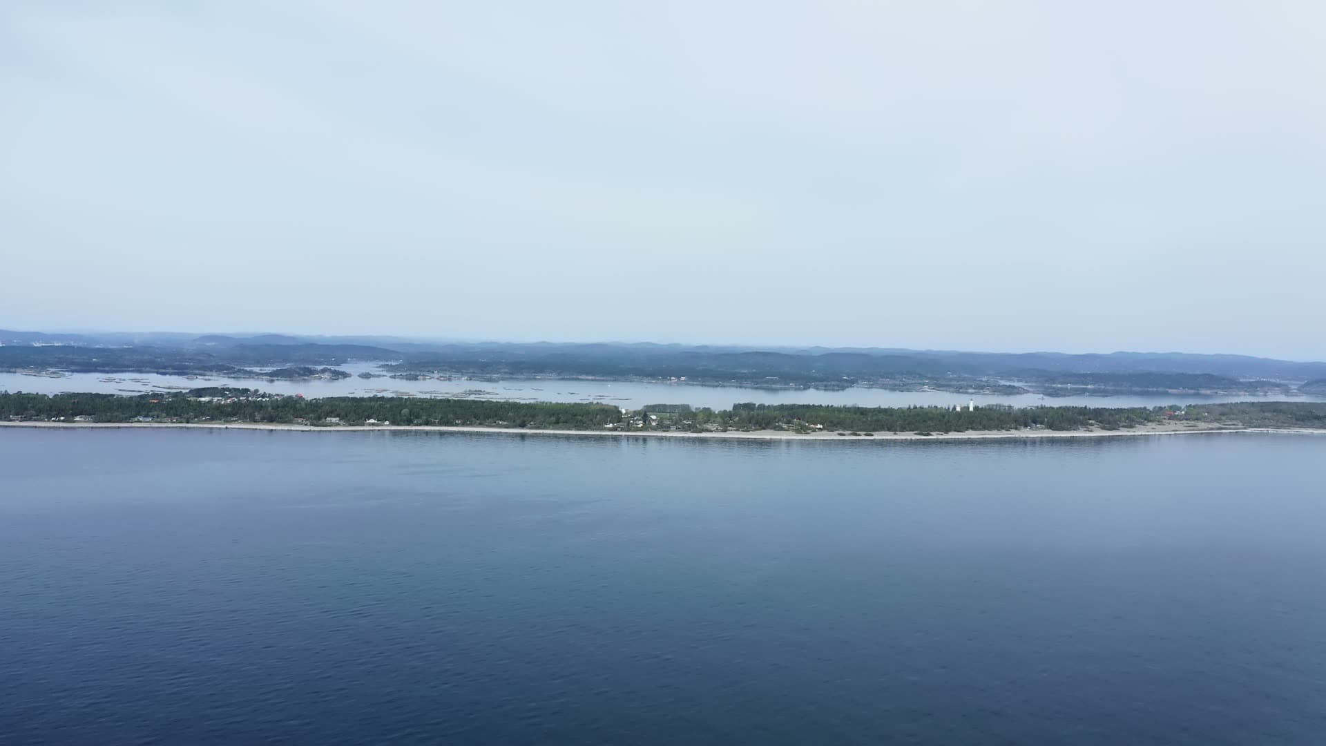 Low wooded island shoreline seen from open sea, Jomfruland, Norway