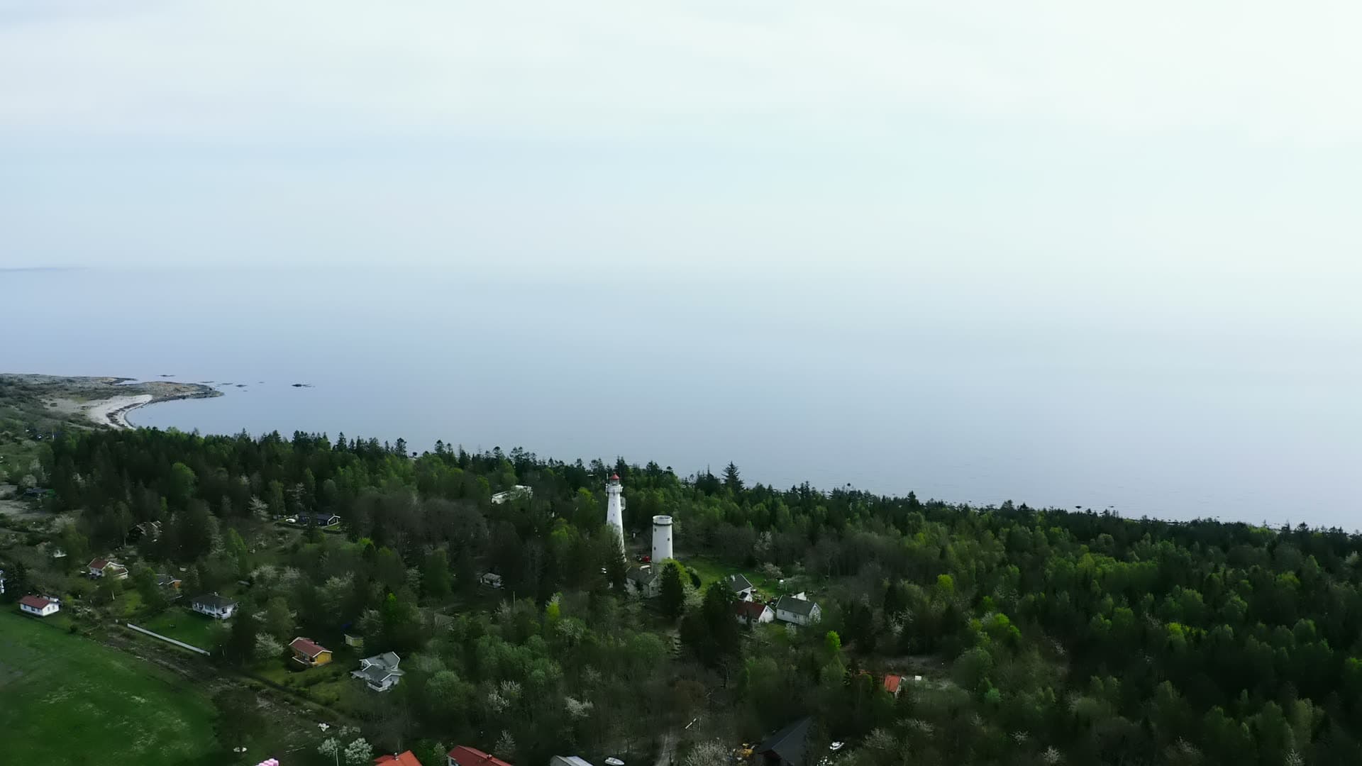Two lighthouse towers above wooded island houses, Jomfruland, Norway