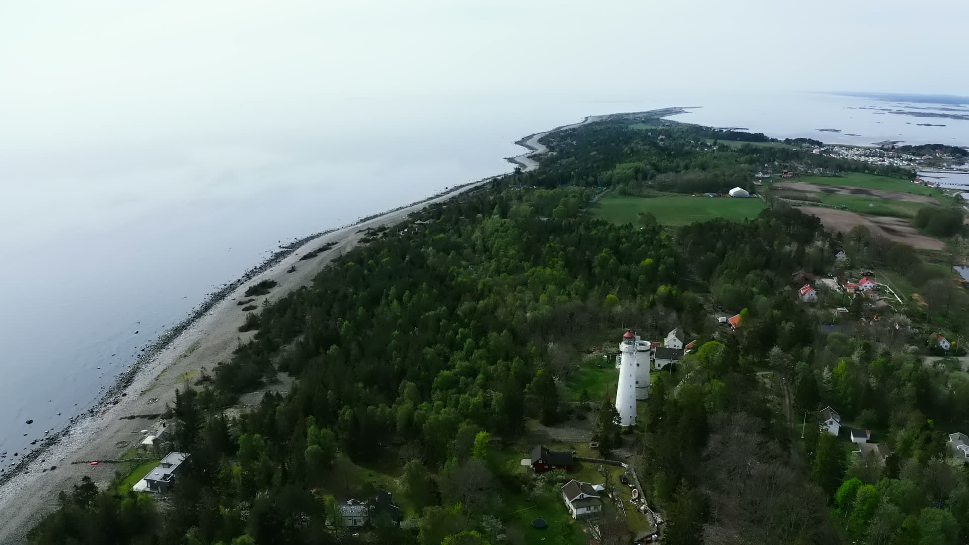 White lighthouse above pebble beach and spit, Jomfruland, Norway