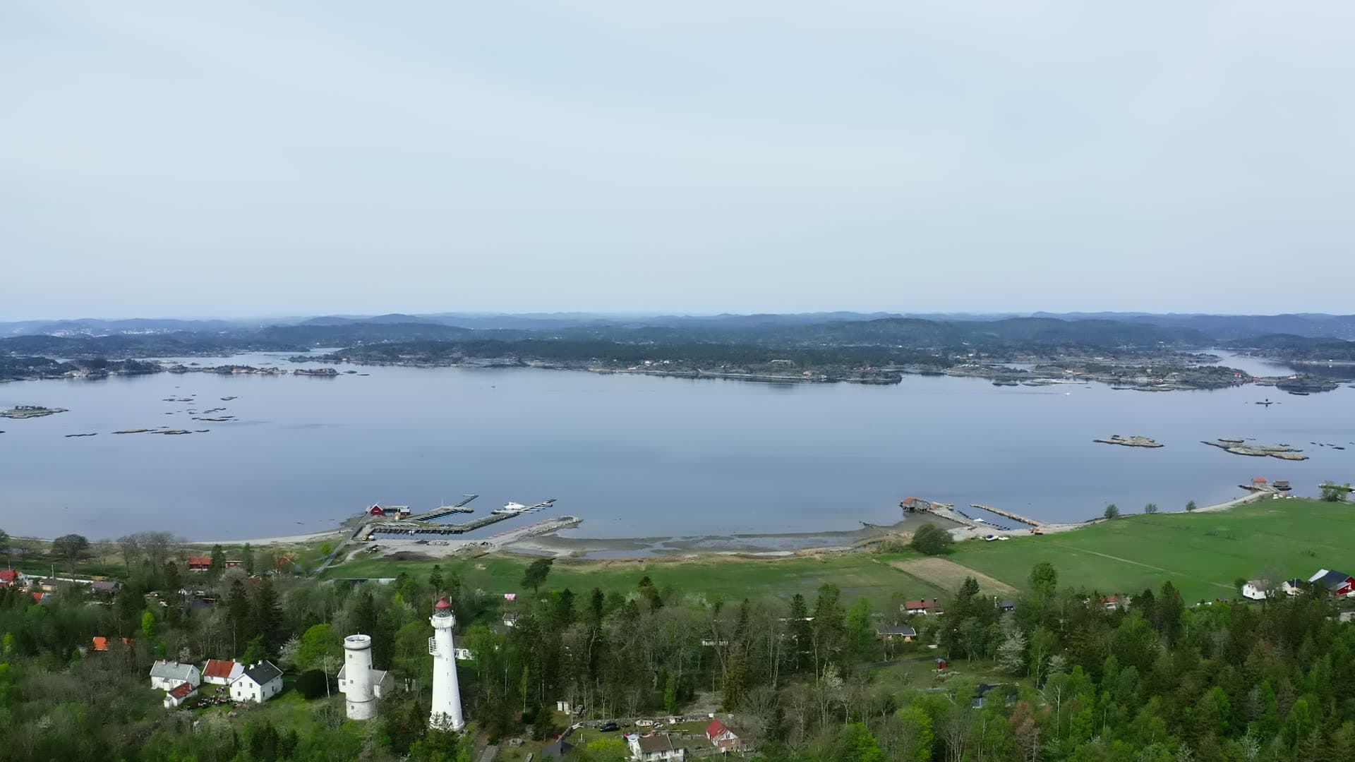 Two white lighthouse towers above marina and fields, Jomfruland, Norway