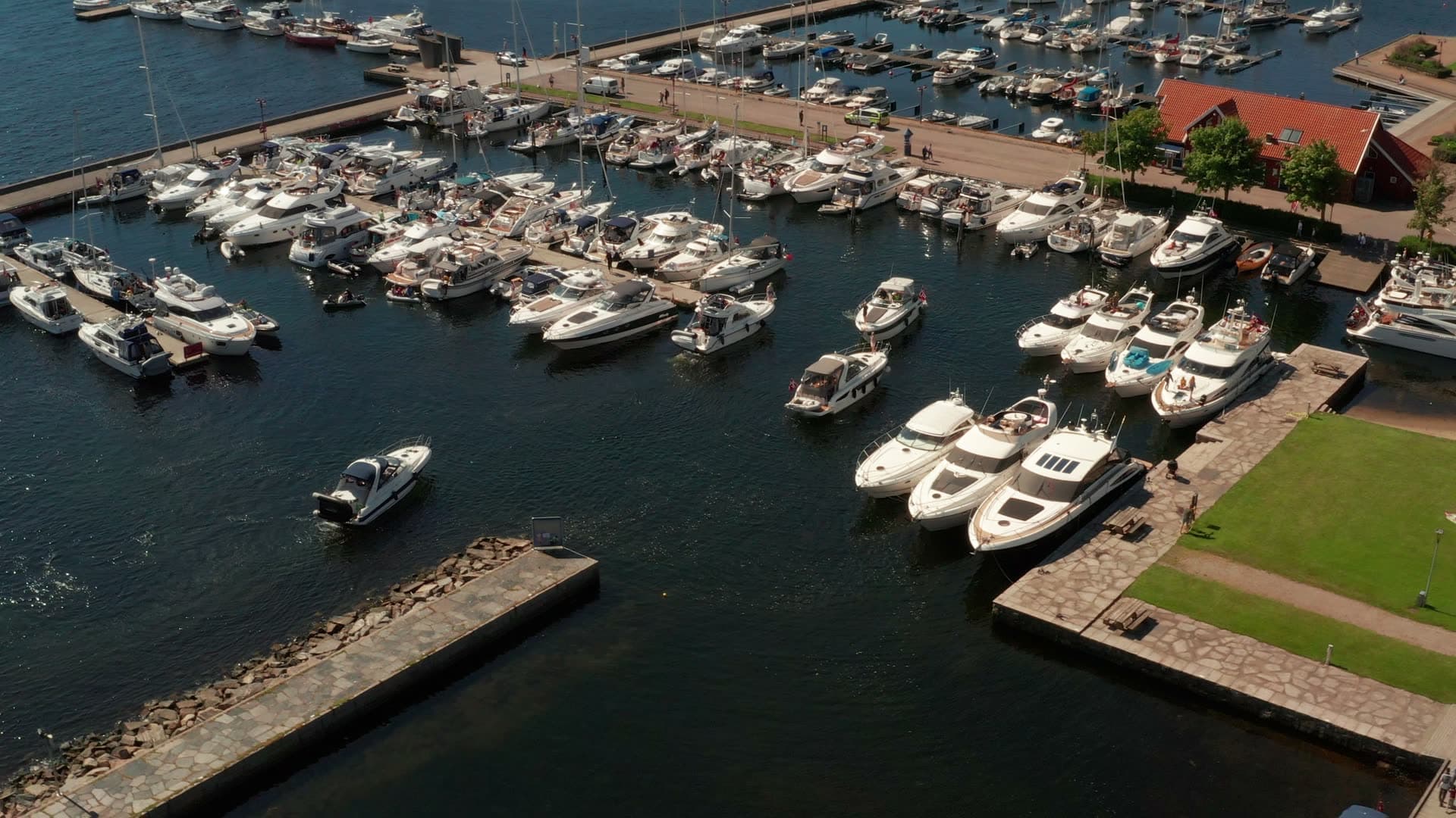Motorboat leaving packed marina by lawn, Kristiansand, Norway