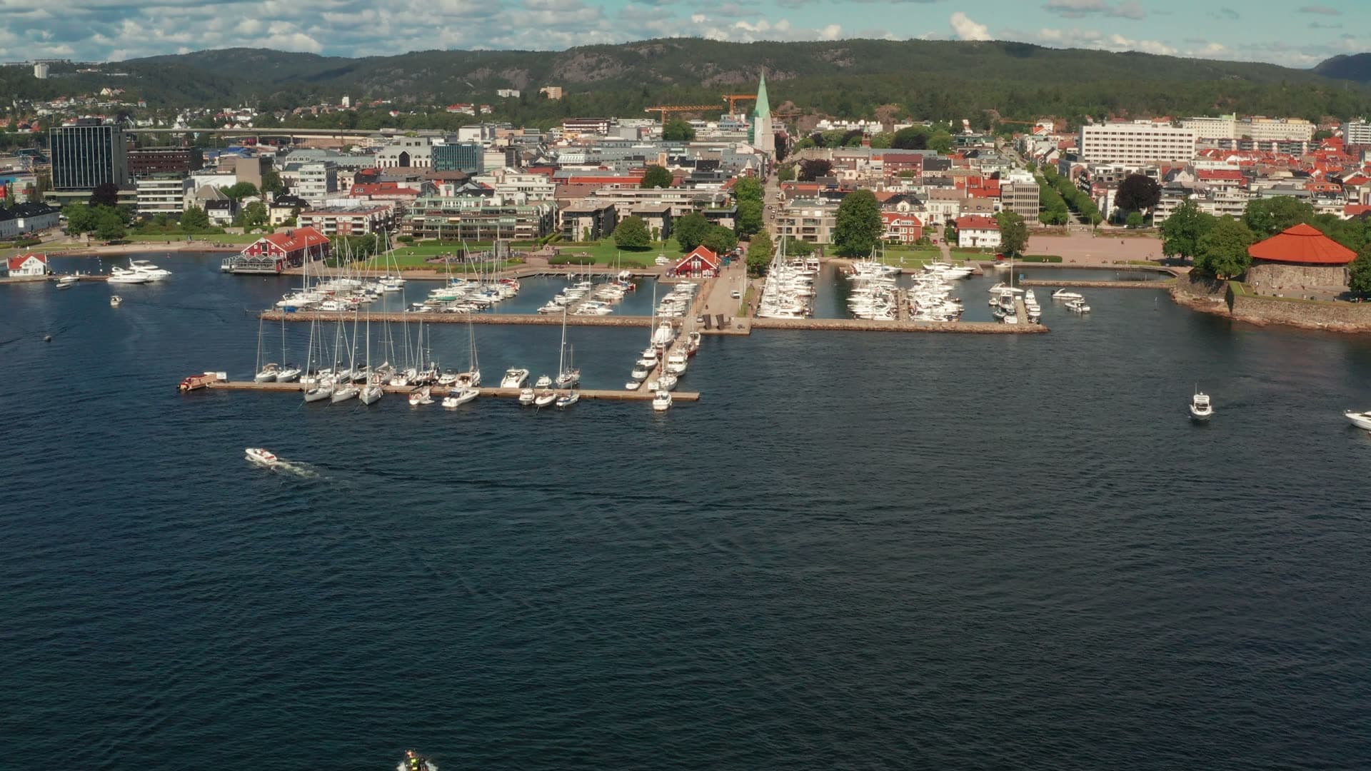 Speedboat crossing bay toward marina piers, Kristiansand, Norway
