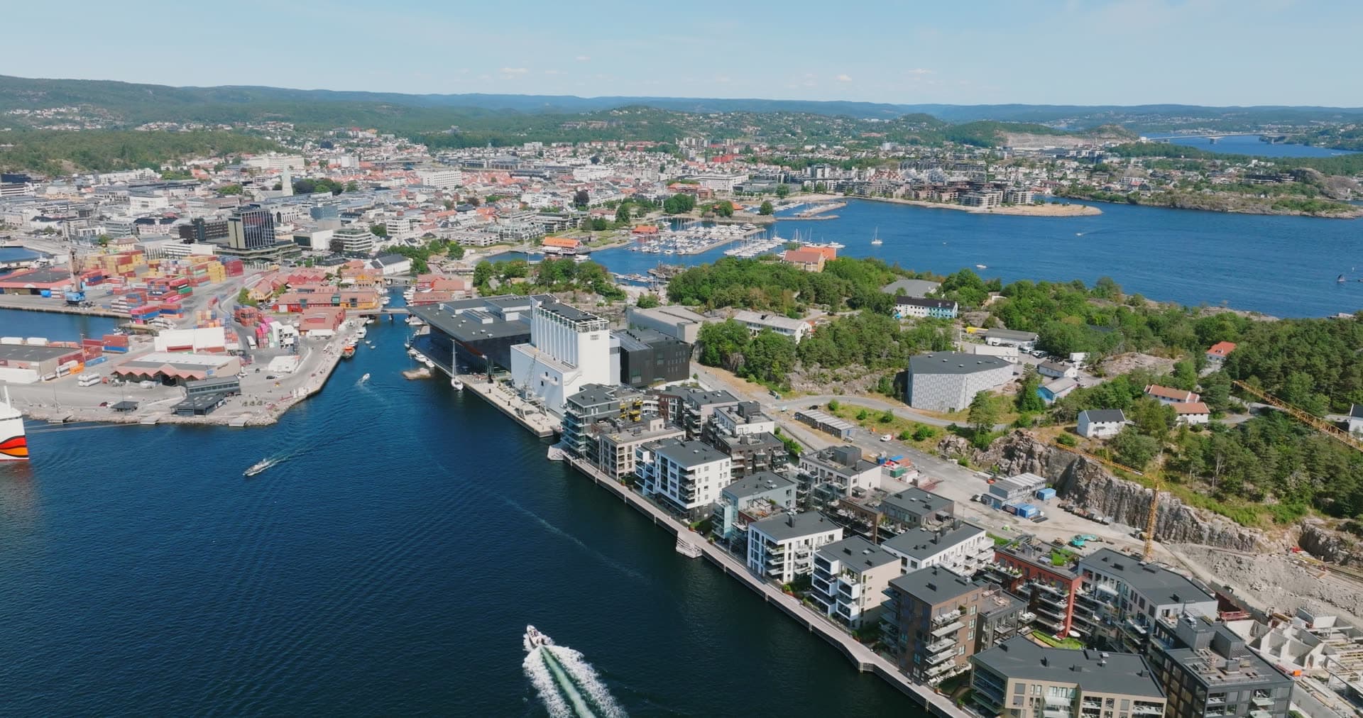 Speedboat wake past waterfront apartments, Kristiansand, Norway