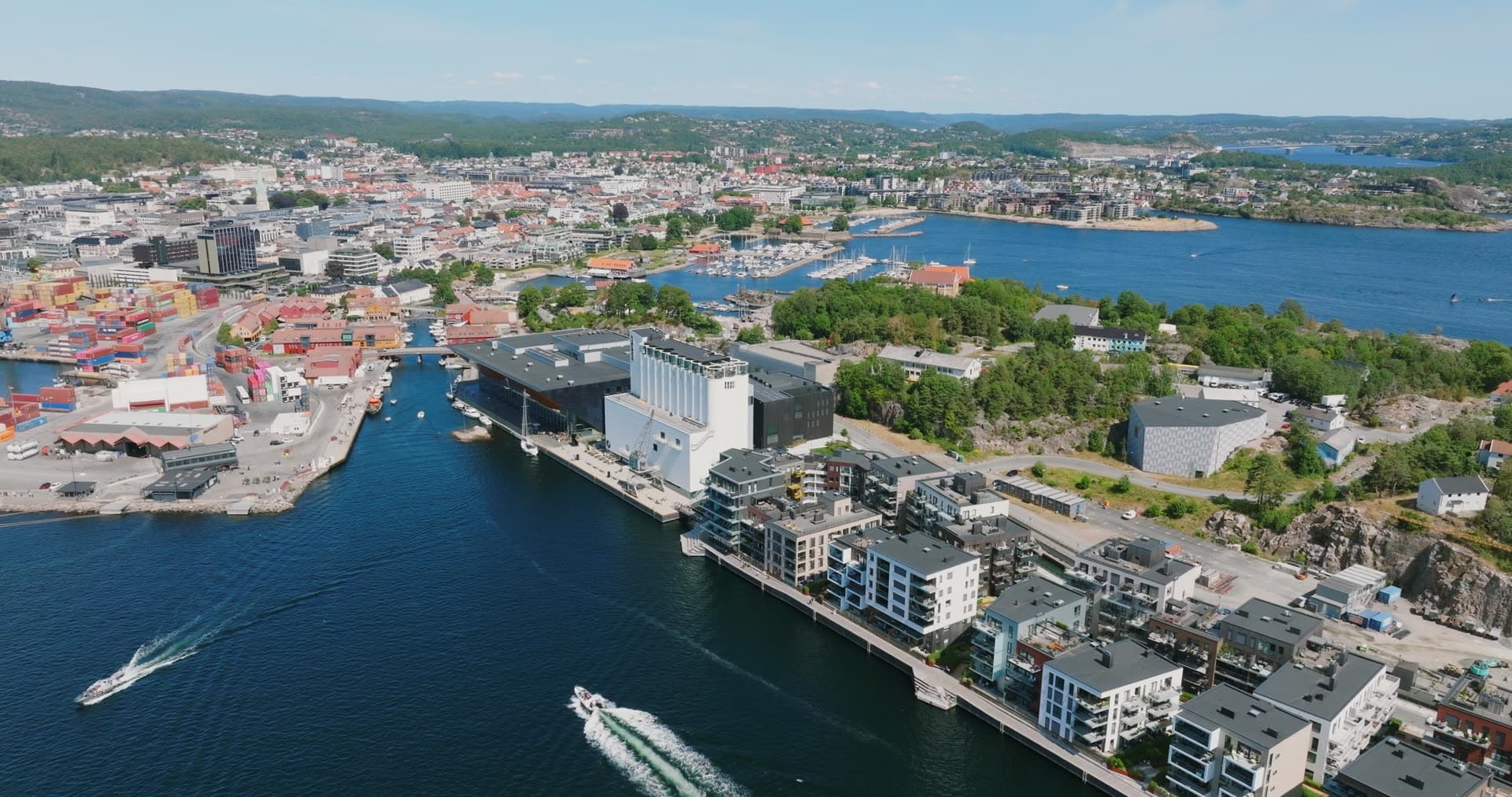 Speedboats passing waterfront apartments and silos, Kristiansand, Norway