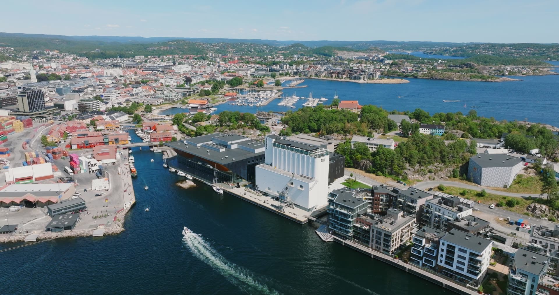Boat wake past grain silos and waterfront flats, Kristiansand, Norway