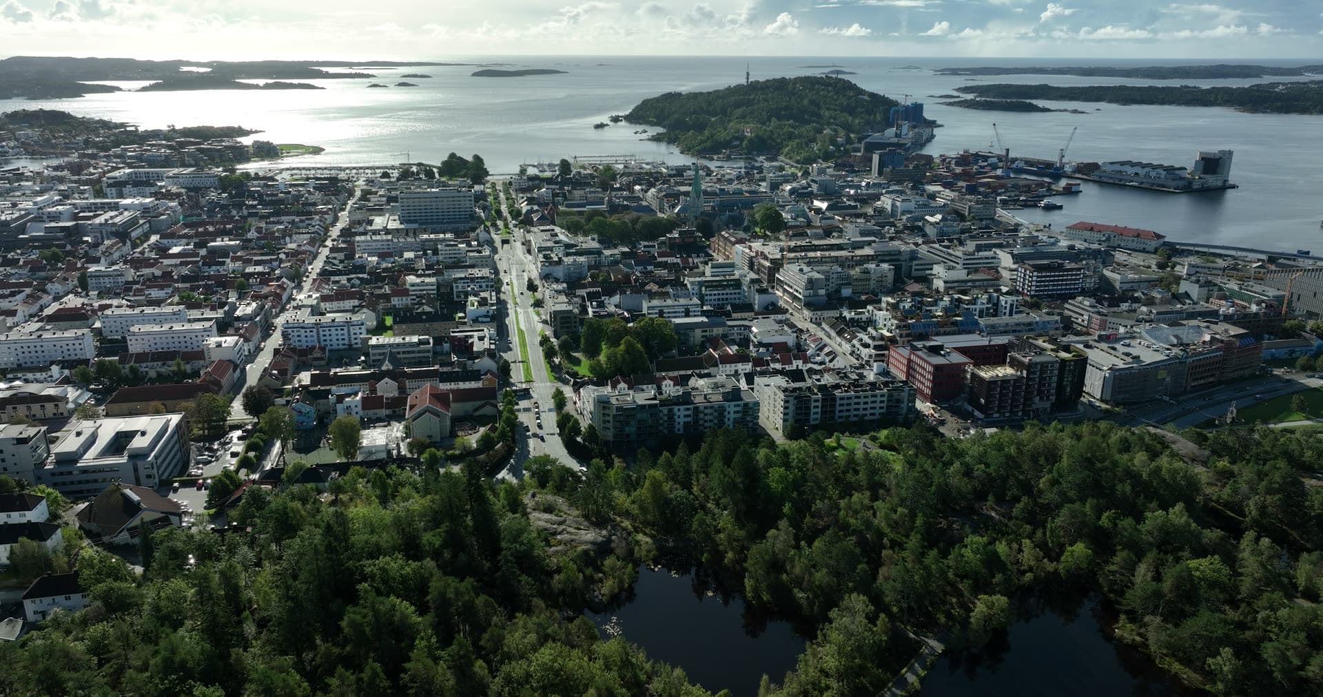 Forest pond, city grid and port cranes, Kristiansand, Norway