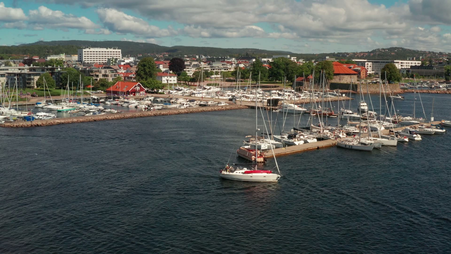 Sailboat leaving marina past breakwater, Kristiansand, Norway