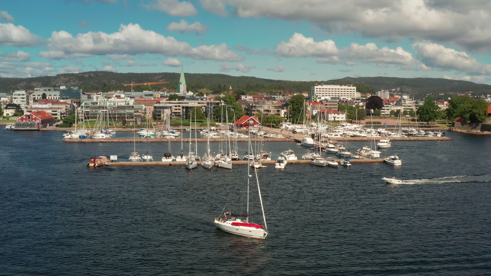 Sailboat leaving marina past town quay, Kristiansand, Norway
