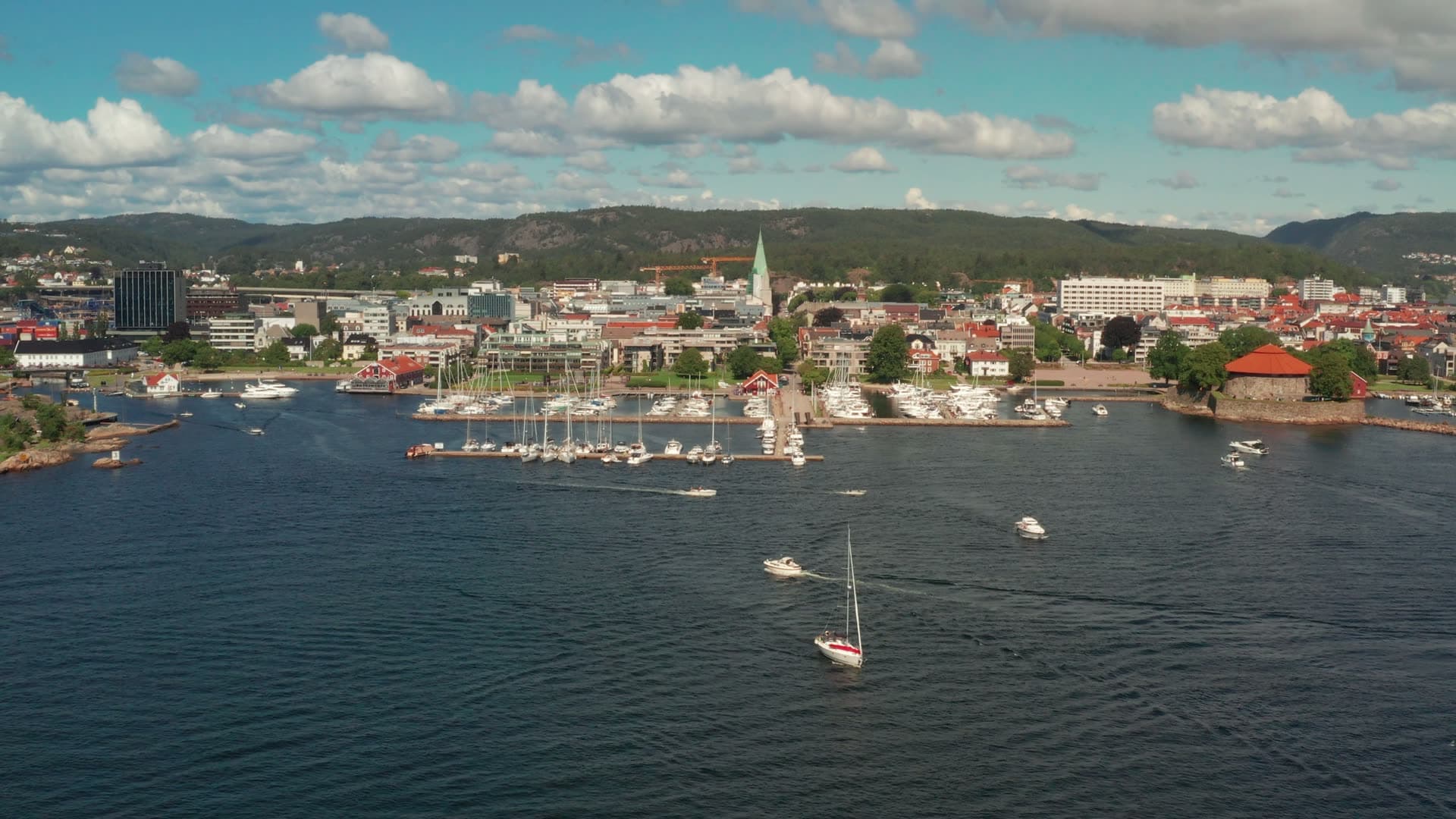 Sailboat crossing harbour past marina docks, Kristiansand, Norway