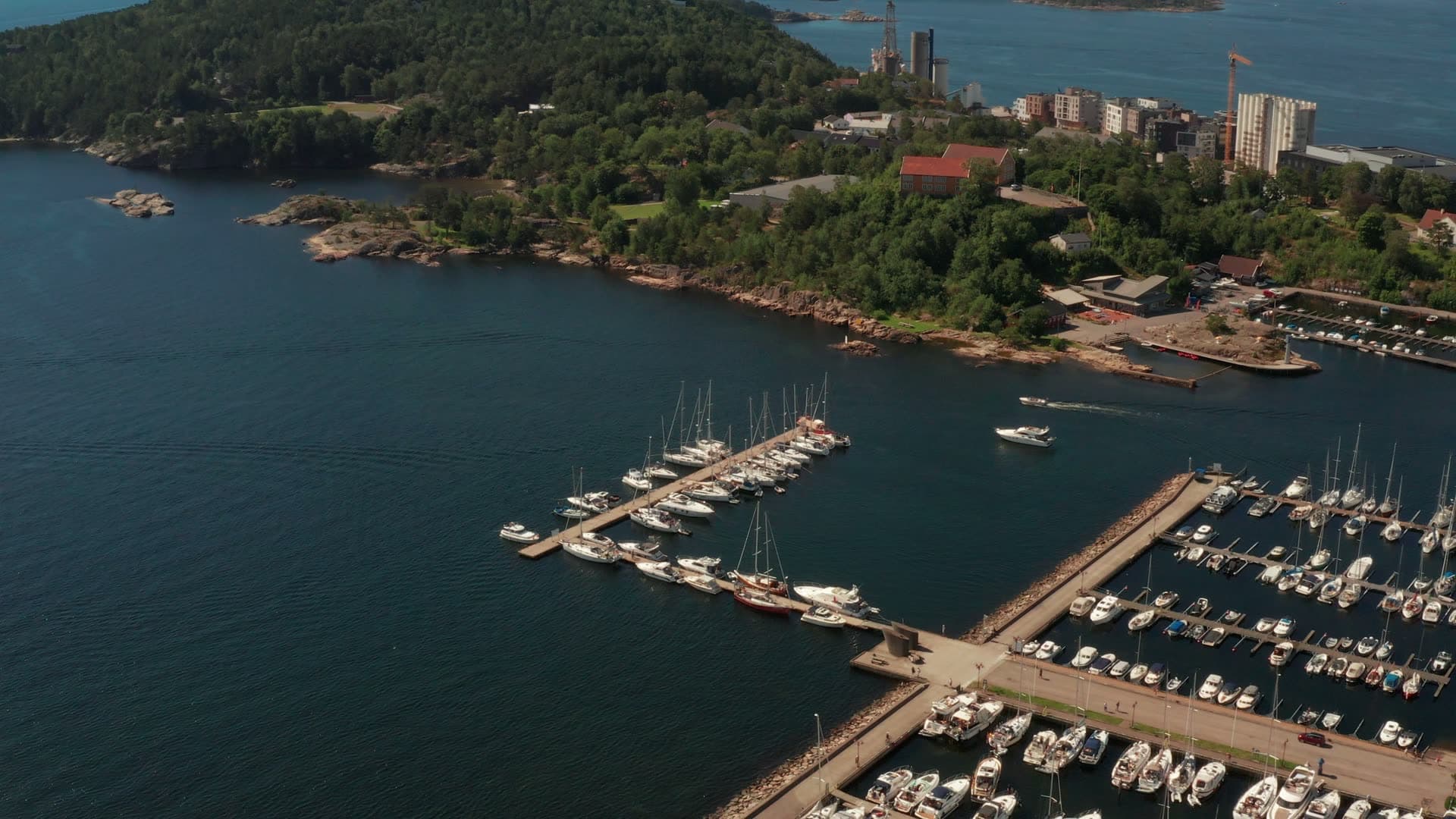 Motorboat leaving marina by rocky point, Kristiansand, Norway