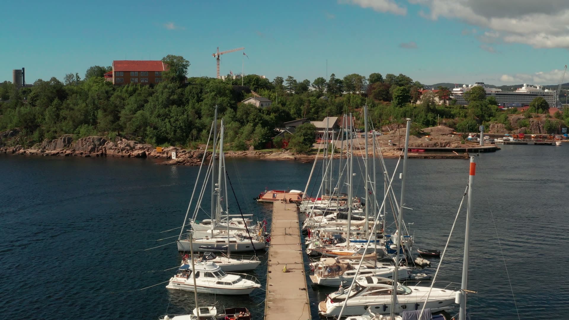 Sailboats along pier, crane on rocky shore, Kristiansand, Norway