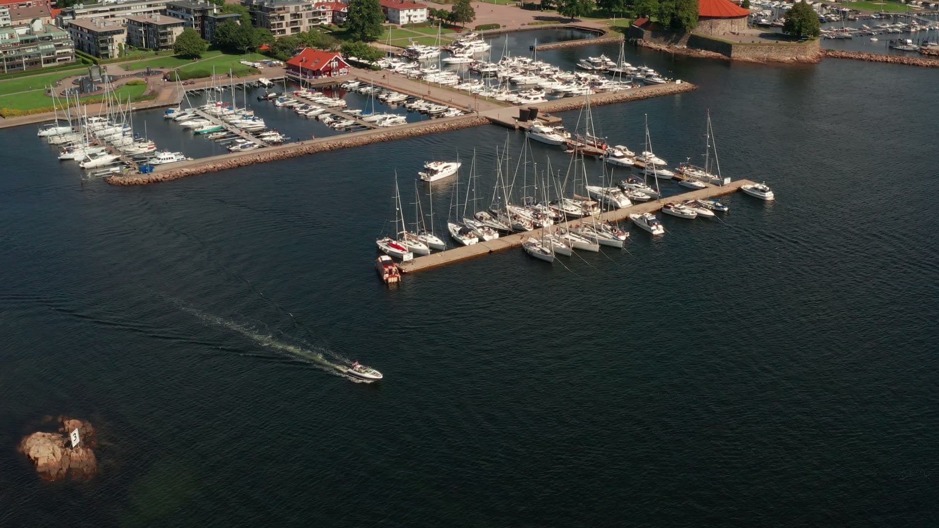 Motorboat wake past marina breakwater, Kristiansand, Norway