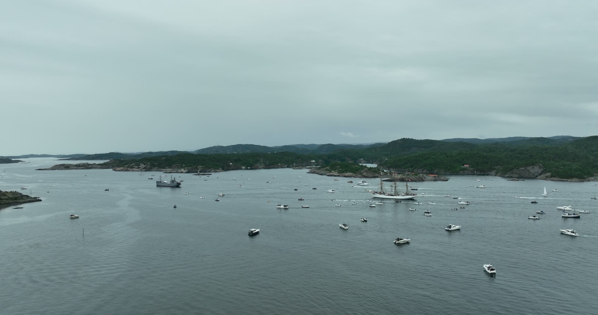 Tall ship escorted by boat crowd in fjord, Kristiansand, Norway