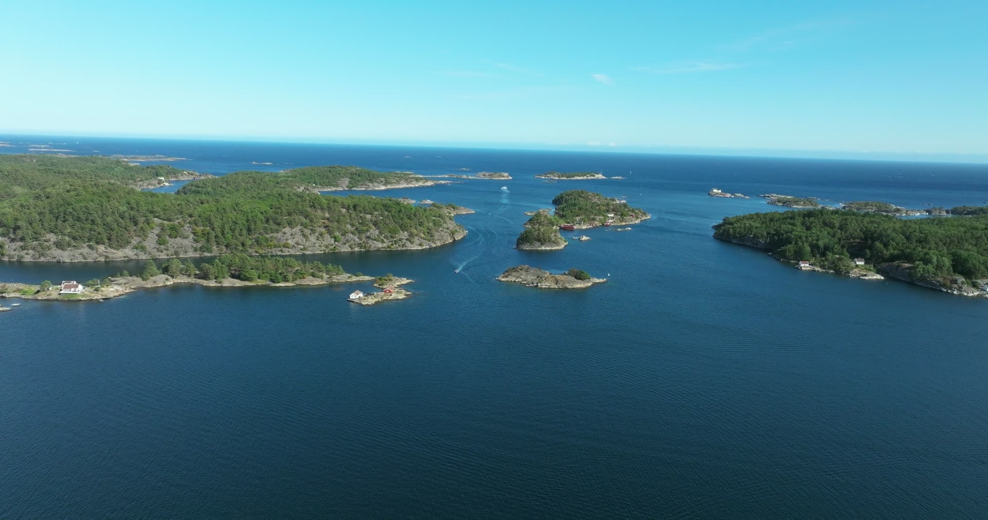 Small boat in strait between wooded islets, Lillesand, Norway