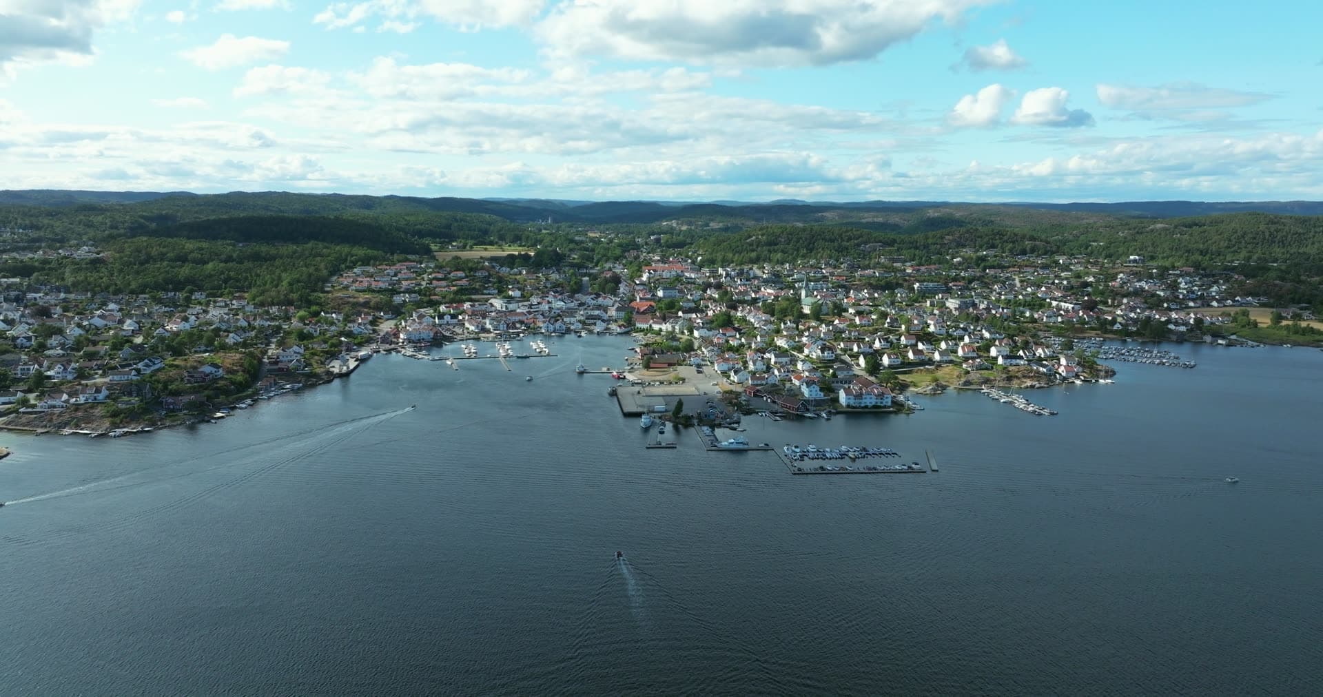 Marina piers and boat wakes off white houses, Lillesand, Norway