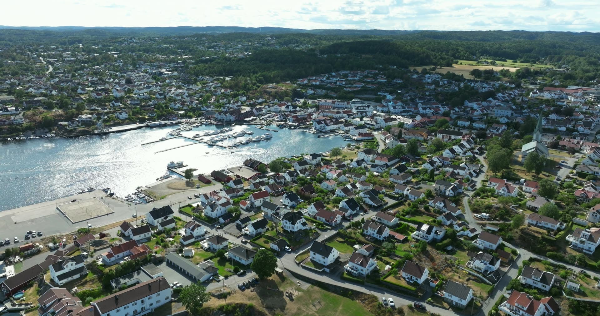 White church spire above houses and boat harbour, Lillesand, Norway