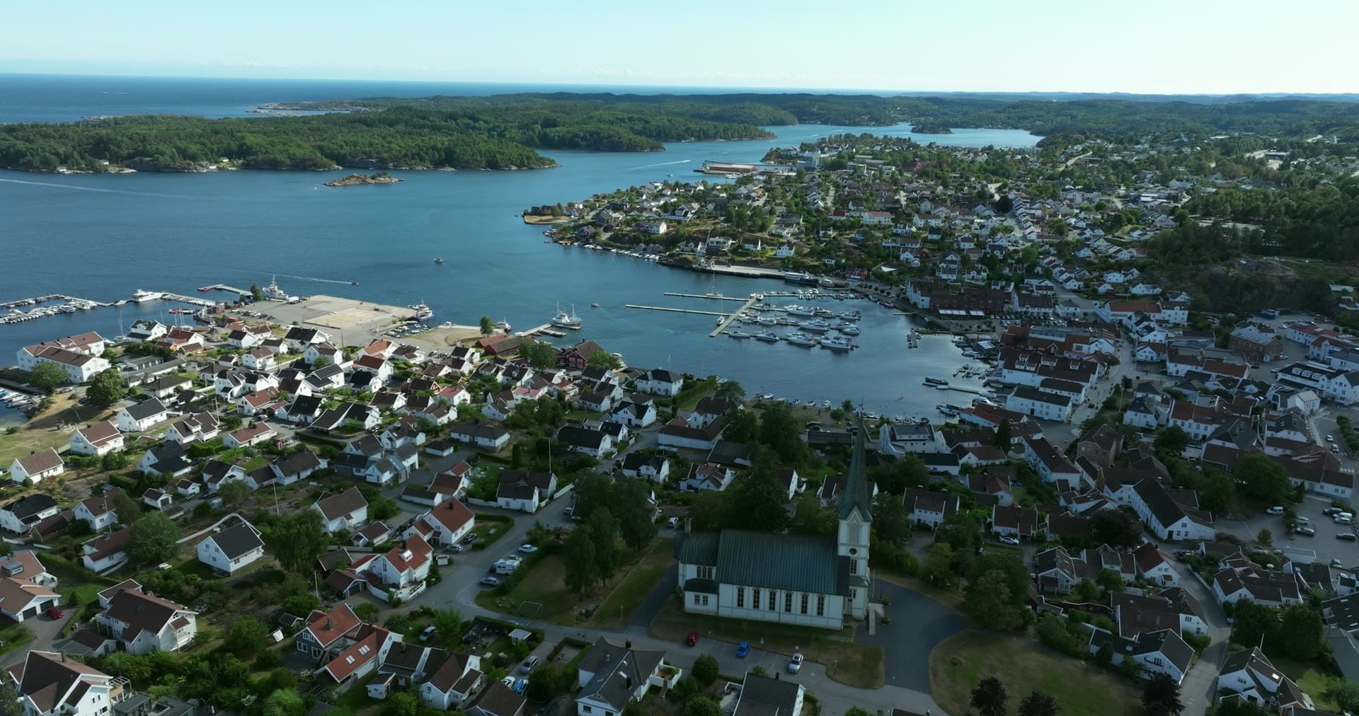 Church spire above white houses and marina, Lillesand, Norway
