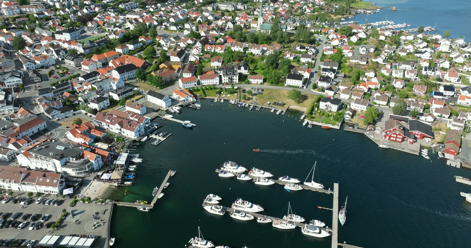 Motorboats at marina pontoons and church spire, Lillesand, Norway
