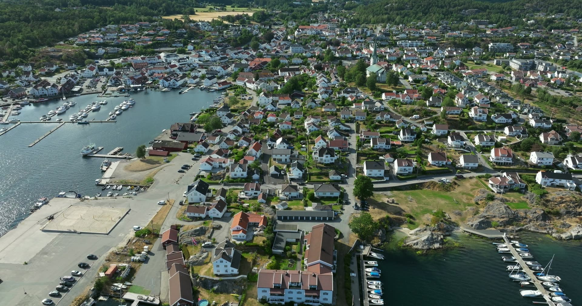 Boat leaving quay past marina and white houses, Lillesand, Norway