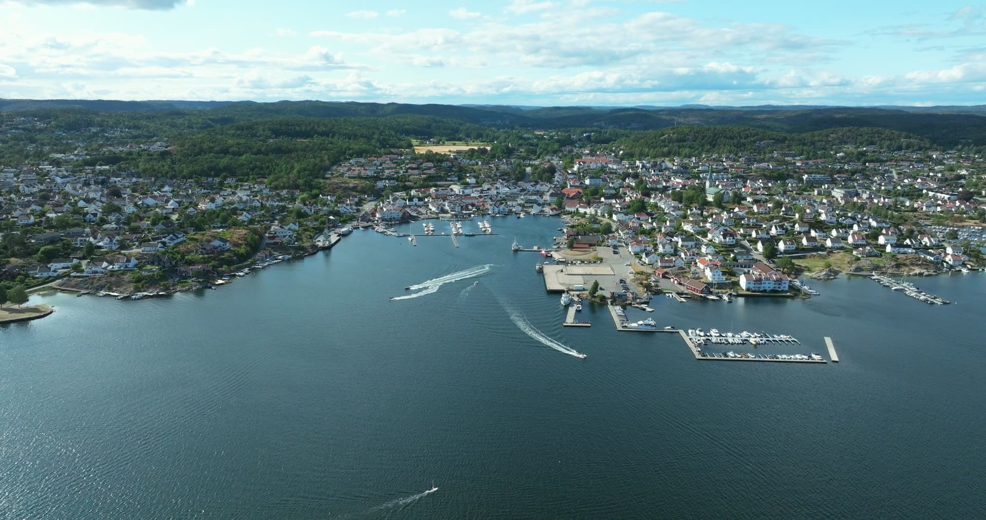 Speedboats leaving wakes past marina piers, Lillesand, Norway