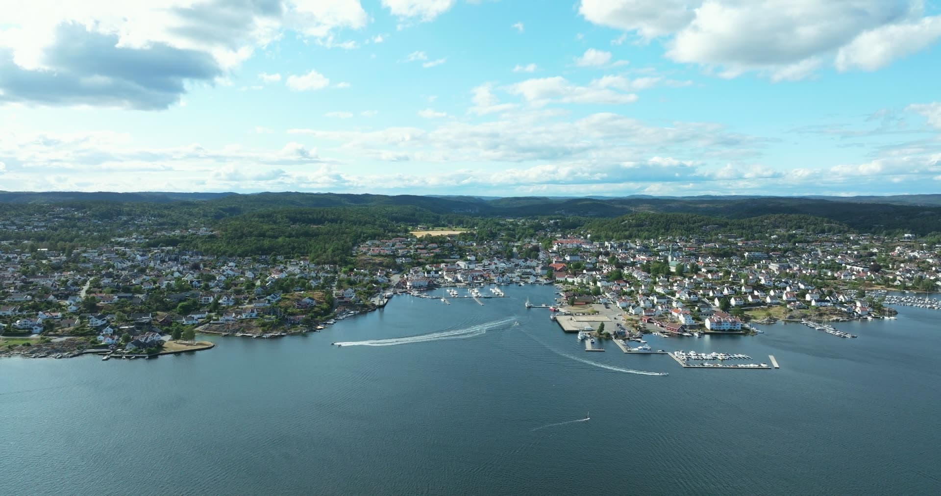 Speedboats leaving wakes off town marina, Lillesand, Norway