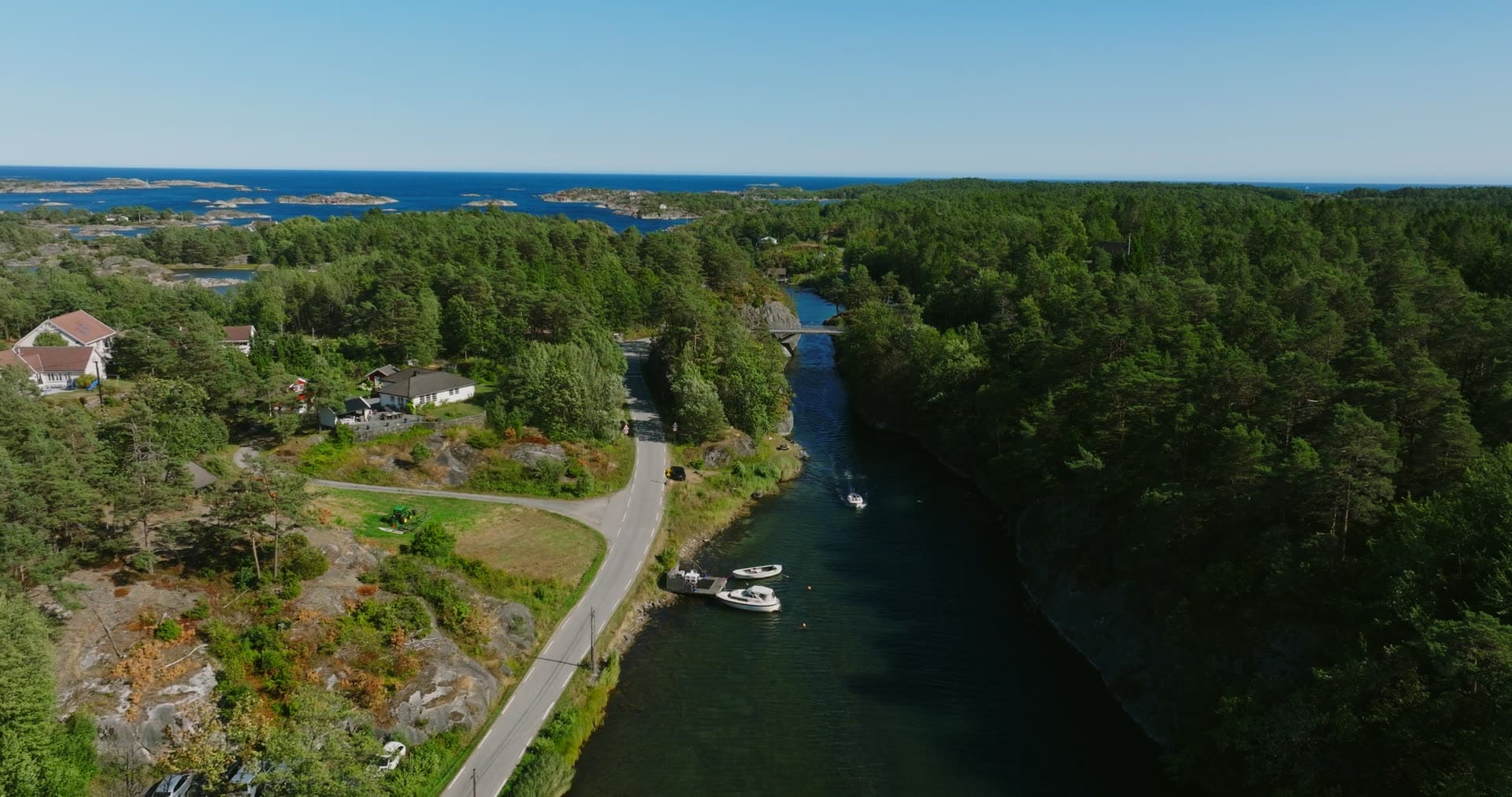 Motorboats moored along the wooded channel, Lillesand, Norway