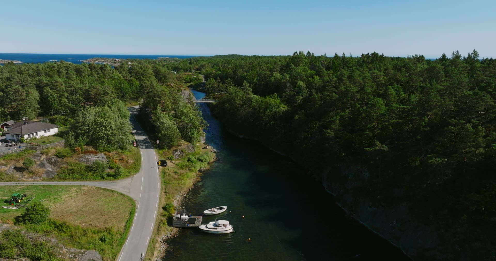 Two motorboats at a quay on the wooded canal, Lillesand, Norway
