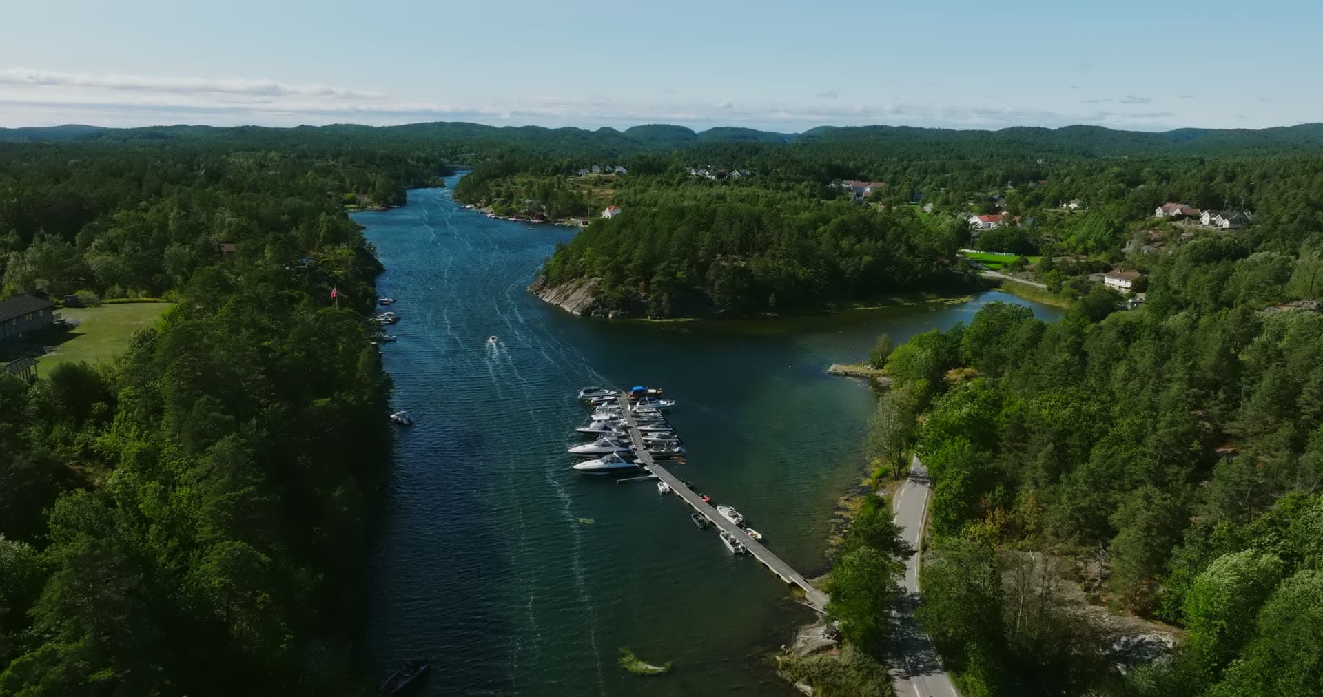 Boat jetty on the inlet below the wooded hills, Lillesand, Norway