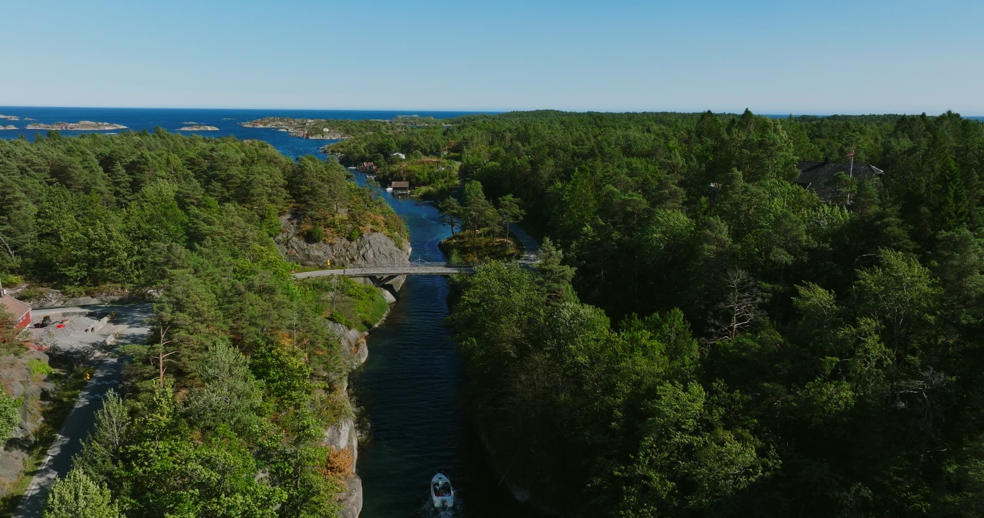 Motorboat passing under the canal bridge, Lillesand, Norway