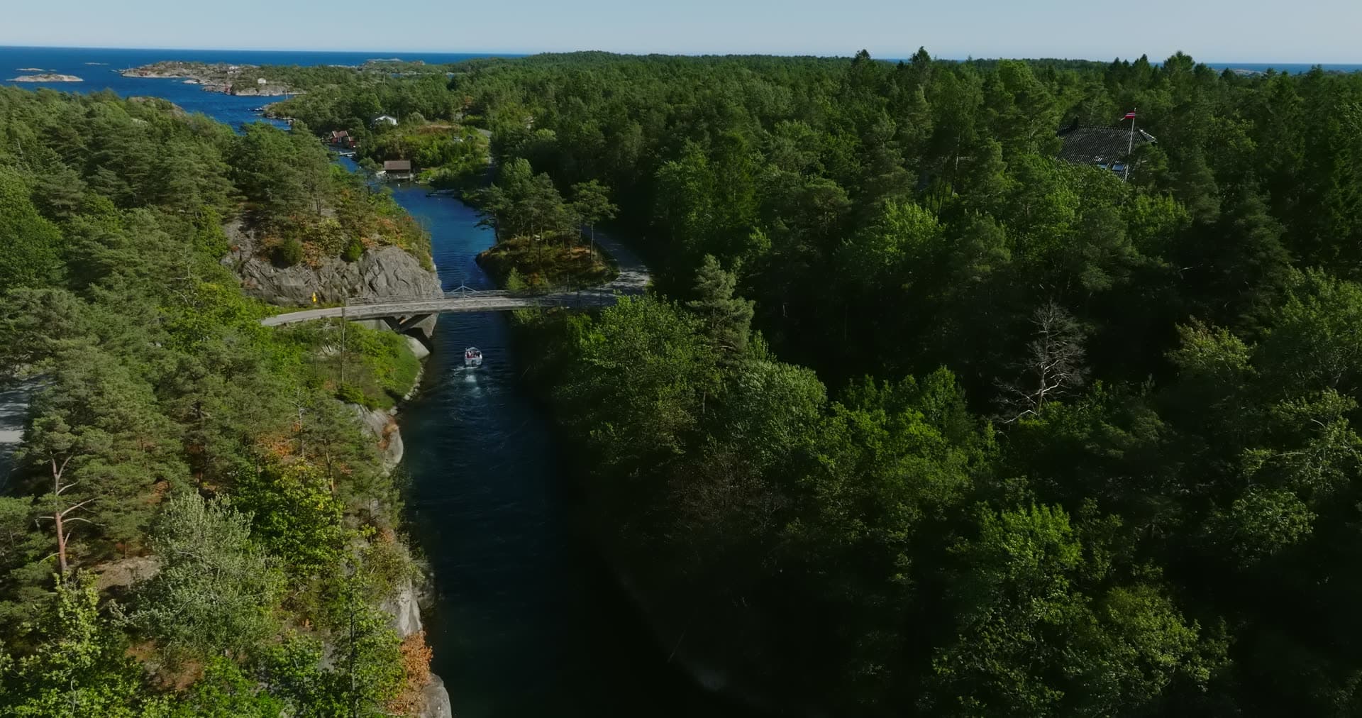 Boat heading seaward through the rock cut, Lillesand, Norway